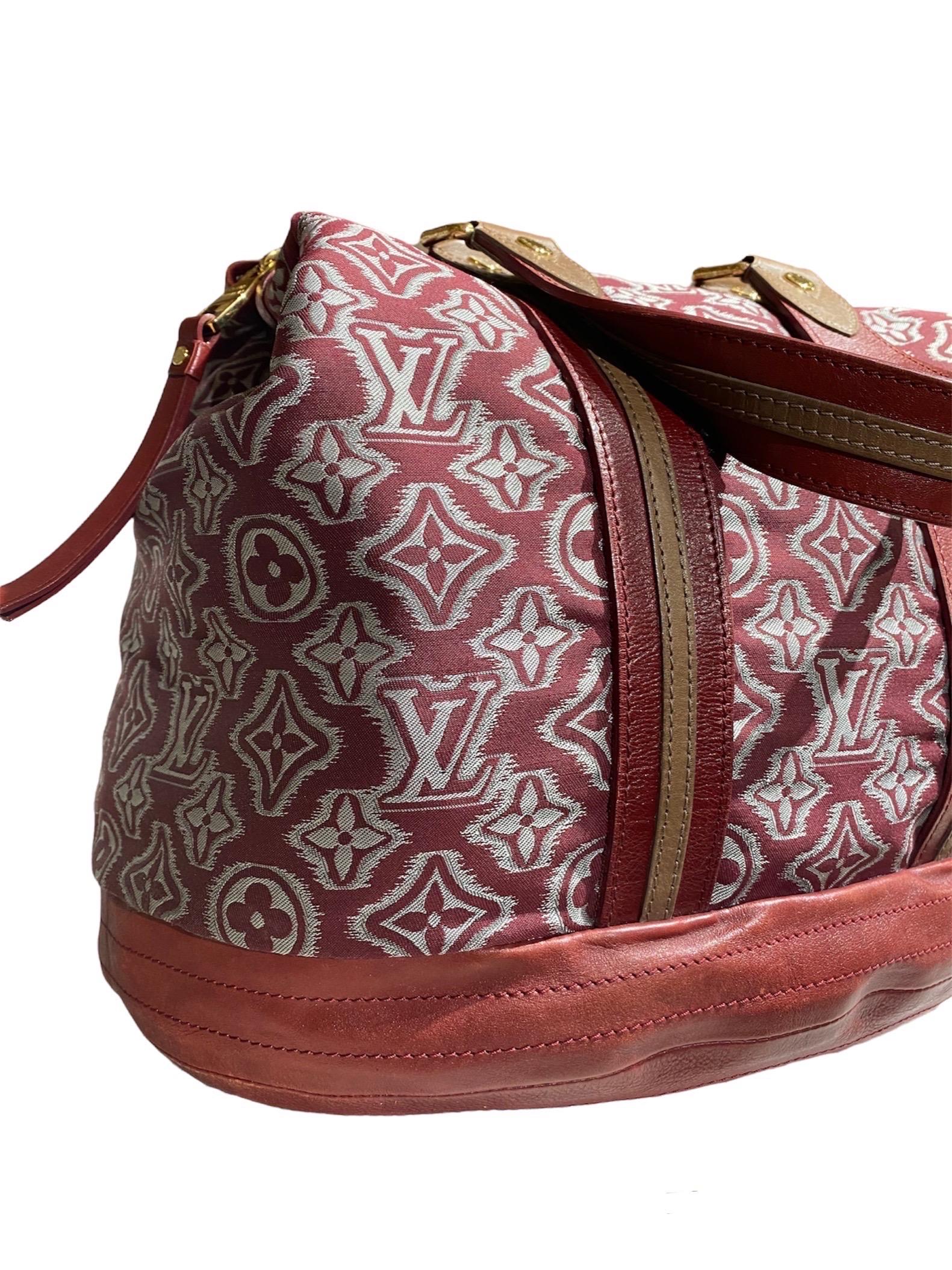 Borsa firmata Louis Vuitton modello Aviator collezione 2010, realizzata in tessuto con inserti in pelle rossa e hardware dorato.

La borsa presenta un doppio manico in pelle, una chiusura a zip e una tracolla in pelle regolabile e rimovibile di 3 cm