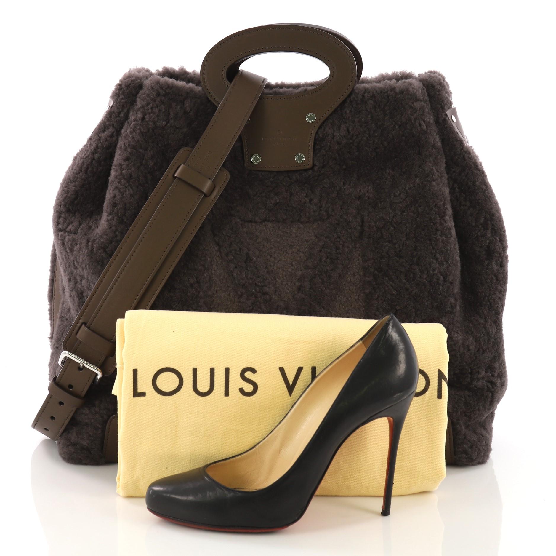 This Louis Vuitton Haut Cabas Shearling, crafted from gray shearling and brown leather, features dual top leather handles and silver-tone hardware. It opens to a brown microfiber interior with side slip pockets. Authenticity code reads: FO2183.
