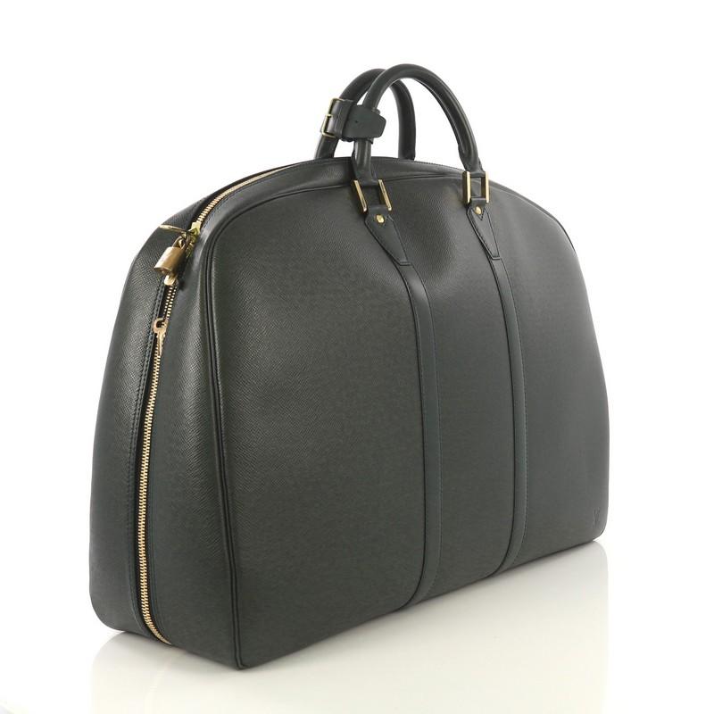 This Louis Vuitton Helanga Bag Taiga Leather 1 Poche, crafted in green taiga leather, features dual rolled leather handles, subtle LV logo, and gold-tone hardware. Its all-around zip closure opens to a gray microfiber interior with slip pocket.