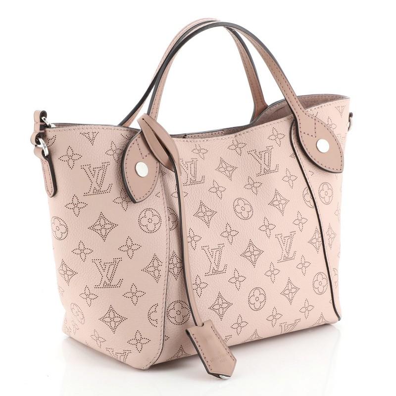 This Louis Vuitton Hina Handbag Mahina Leather PM, crafted from pink mahina leather, features dual slim leather handles and silver-tone hardware. Its magnetic snap button closure opens to a pink microfiber interior. Authenticity code reads: DR1128.
