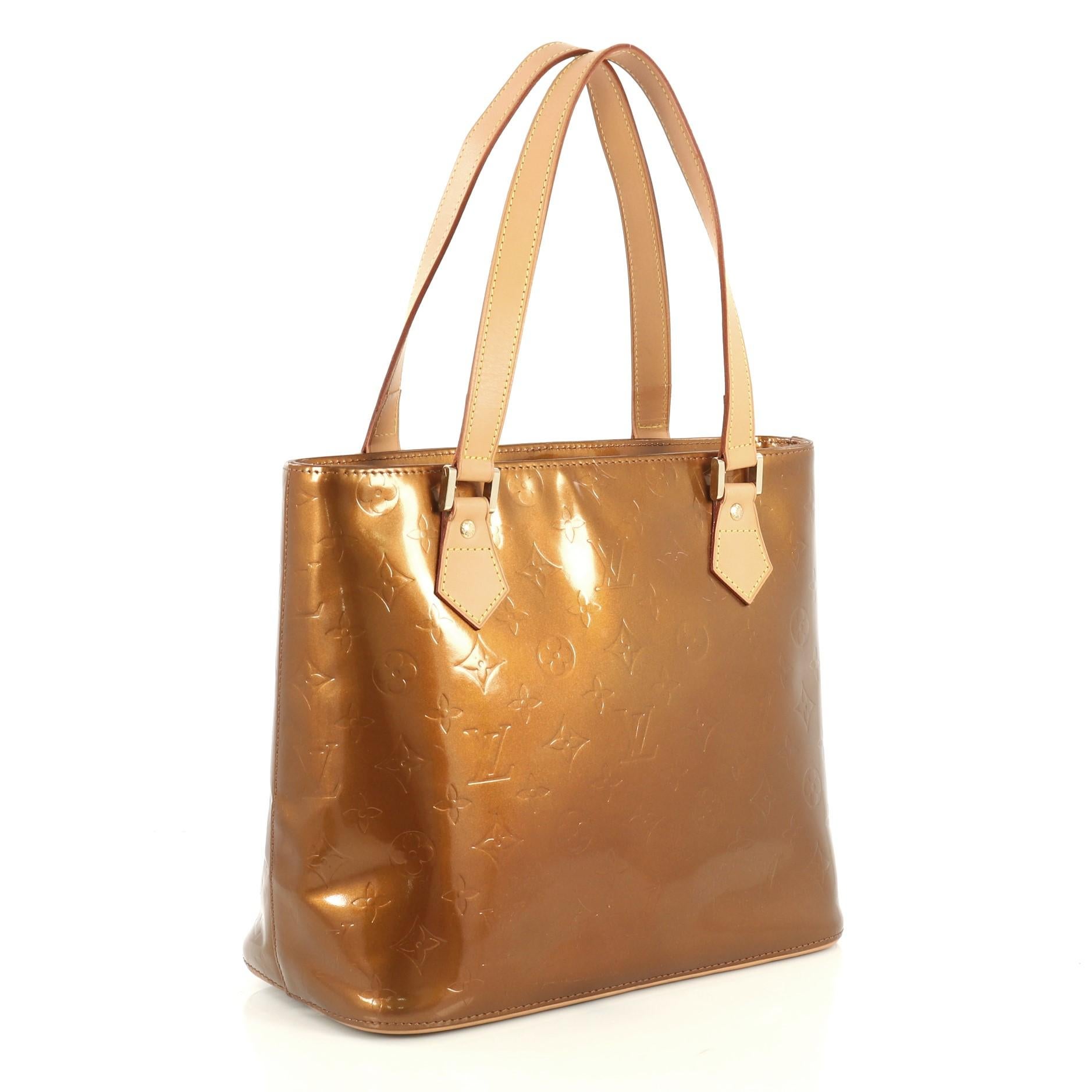 This Louis Vuitton Houston Handbag Monogram Vernis, crafted from brown monogram vernis leather, features dual flat vachetta leather handles, vachetta leather trim, and gold-tone hardware. Its zip closure opens to a brown leather interior with side
