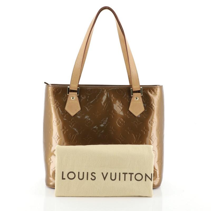 This Louis Vuitton Houston Handbag Monogram Vernis, crafted from brown monogram vernis leather, features dual flat vachetta leather handles, vachetta leather trim, and gold-tone hardware. Its zip closure opens to a brown leather interior with side