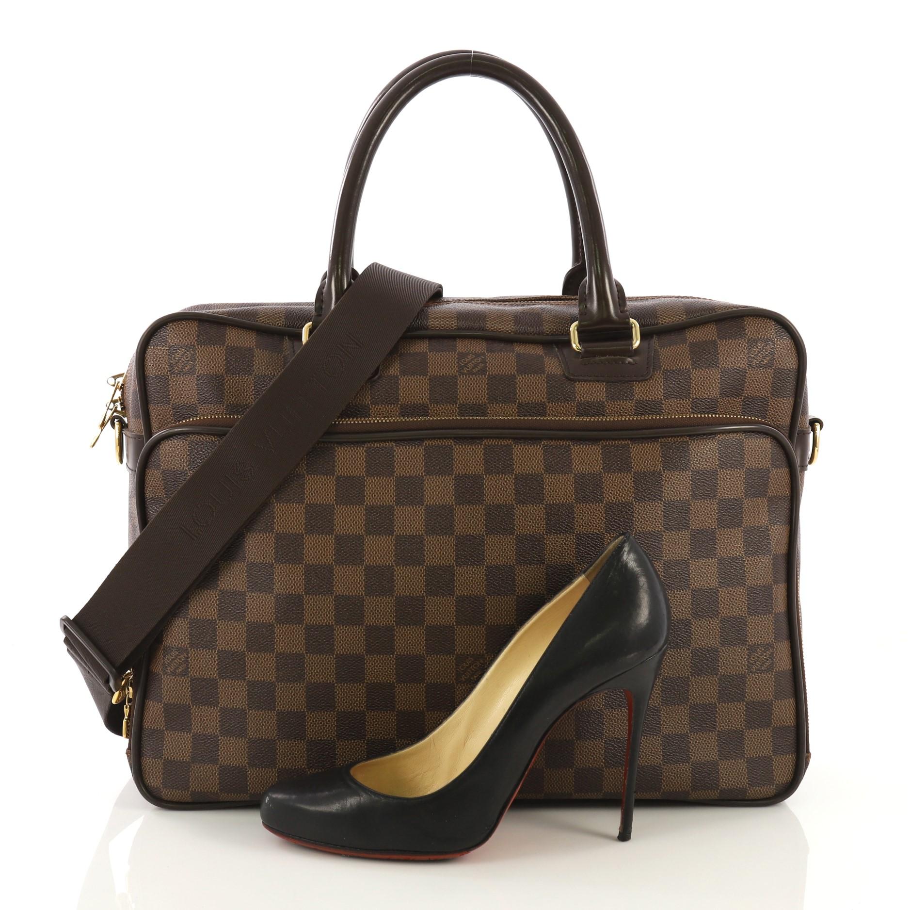 This Louis Vuitton Icare Laptop Bag Damier, crafted from damier ebene coated canvas, features dual rolled leather handles, front zip pocket and gold-tone hardware. Its zip closure opens to a brown fabric interior. Authenticity code reads: AS0029.