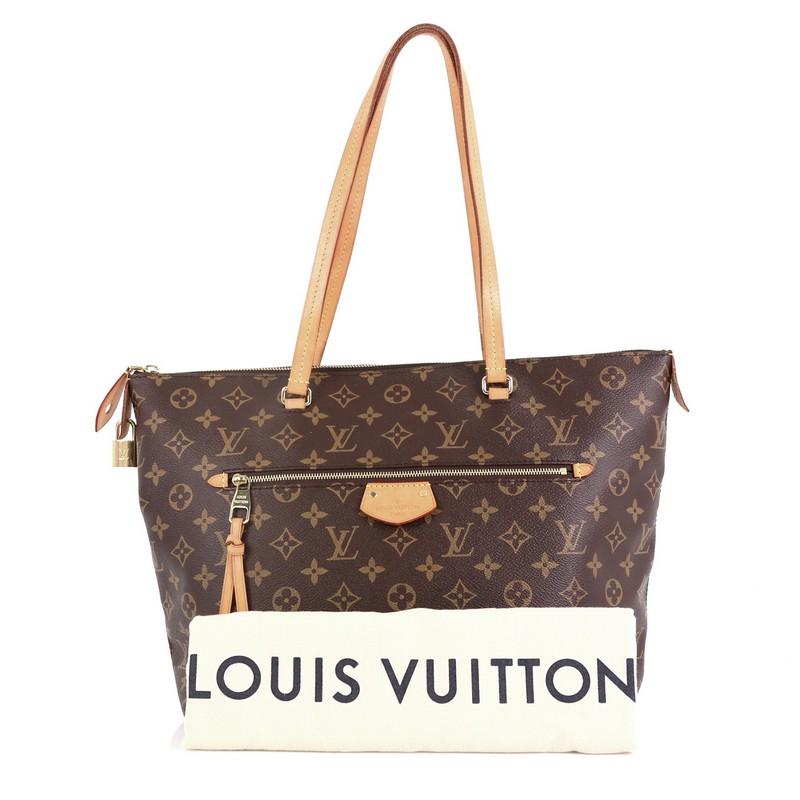 This Louis Vuitton Iena Tote Monogram Canvas MM, crafted from brown monogram coated canvas, features dual flat leather handles, exterior zip pocket, and gold-tone hardware. Its zip closure opens to a red fabric interior with slip pockets.
