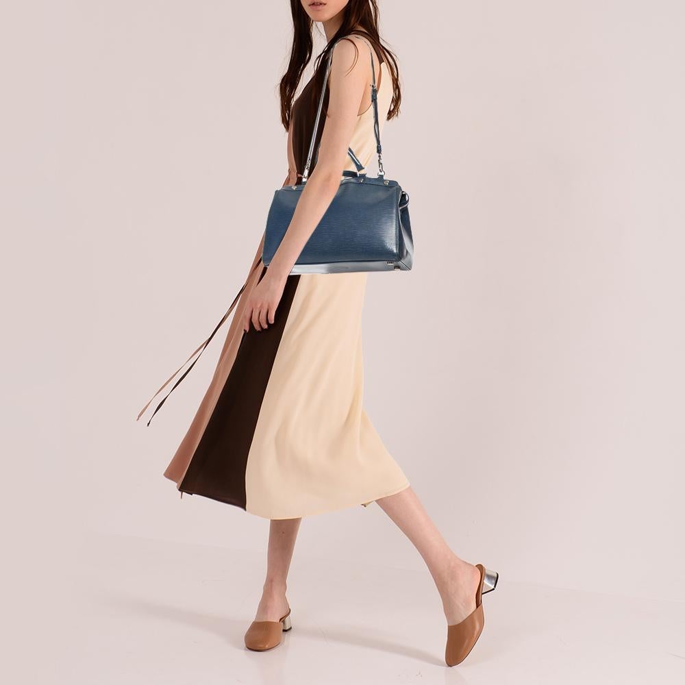 Die feminine Form der Brea von Louis Vuitton ist von der Arzttasche inspiriert. Die aus Epi-Leder gefertigte Tasche ist perfekt verarbeitet. Der Innenraum aus Stoff ist geräumig und wird mit einem Reißverschluss gesichert. Die Tasche hat zwei