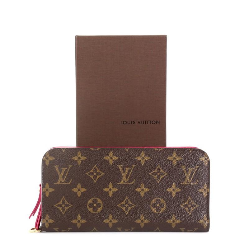 This Louis Vuitton Insolite Wallet Monogram Canvas, crafted from brown monogram coated canvas, features extended leather zip pulls, and gold-tone hardware. Its dual snap closure opens to a pink leather interior with zip pocket and multiple card