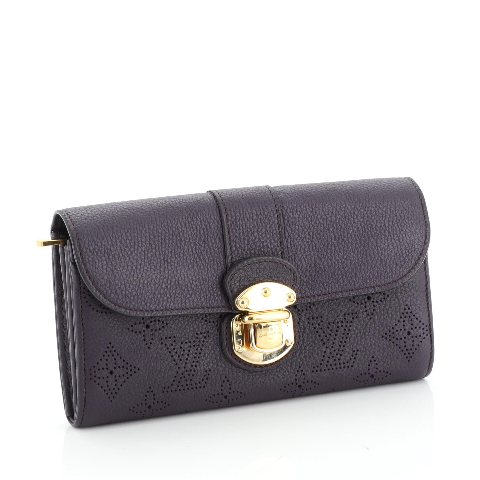This Louis Vuitton Iris Wallet Mahina Leather, crafted from purple monogram mahina leather, features frontal flap with gold-tone hardware. Its push lock closure opens to a purple leather interior with multiple card slots, middle zip compartment, and