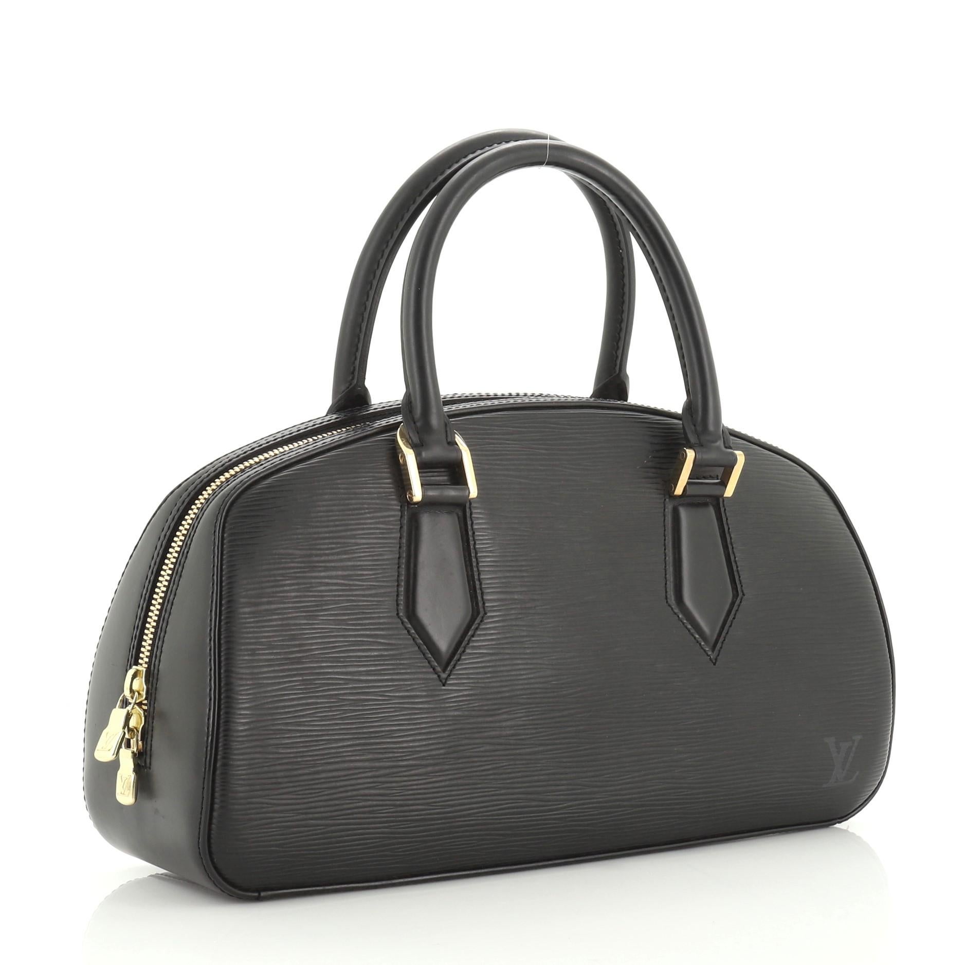 This Louis Vuitton Jasmin Bag Epi Leather, crafted with black epi leather, features dual rolled leather handles, subtle LV logo at the front and gold-tone hardware. Its all-around zip closure opens to a gray microfiber interior with slip pocket.