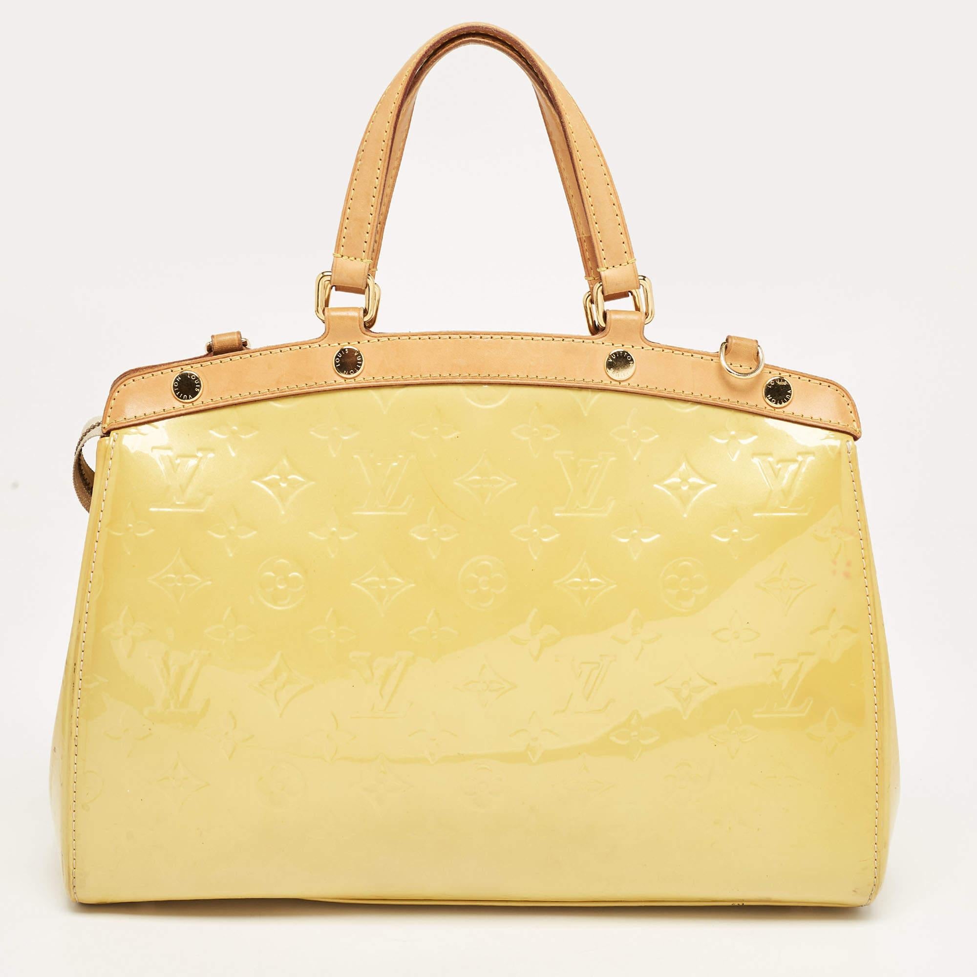 This Brea MM bag from the House of Louis Vuitton will definitely sway you away with its precise shape, style, and design. It is made from Jaune Passion Monogram Vernis into a structured, neat silhouette. It flaunts gold-toned fittings, dual top