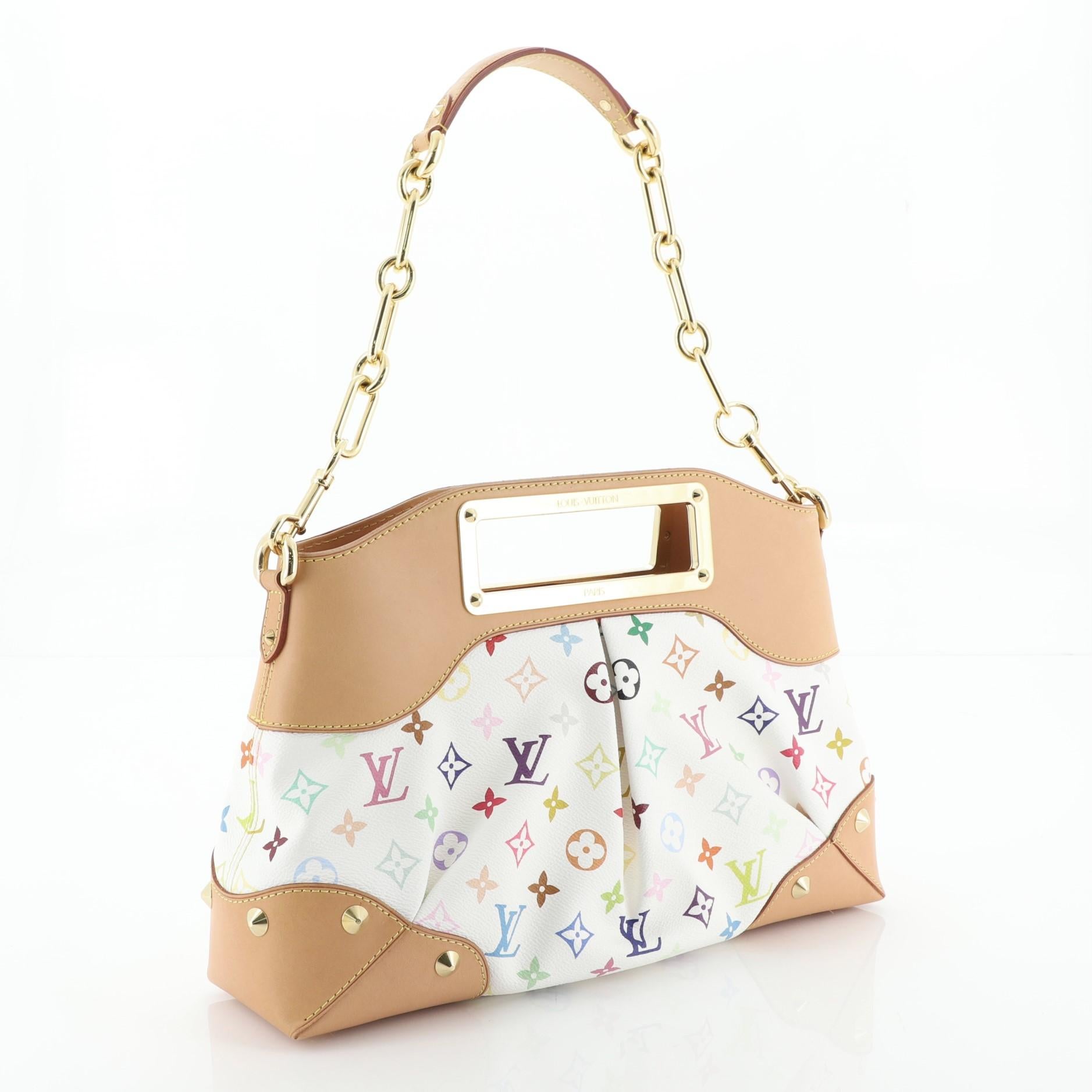 This Louis Vuitton Judy Handbag Monogram Multicolor MM, crafted from white monogram multicolor coated canvas, features chain link strap with leather pad, logo engraved cut-out handles, protective base studs, and gold-tone hardware. Its magnetic snap