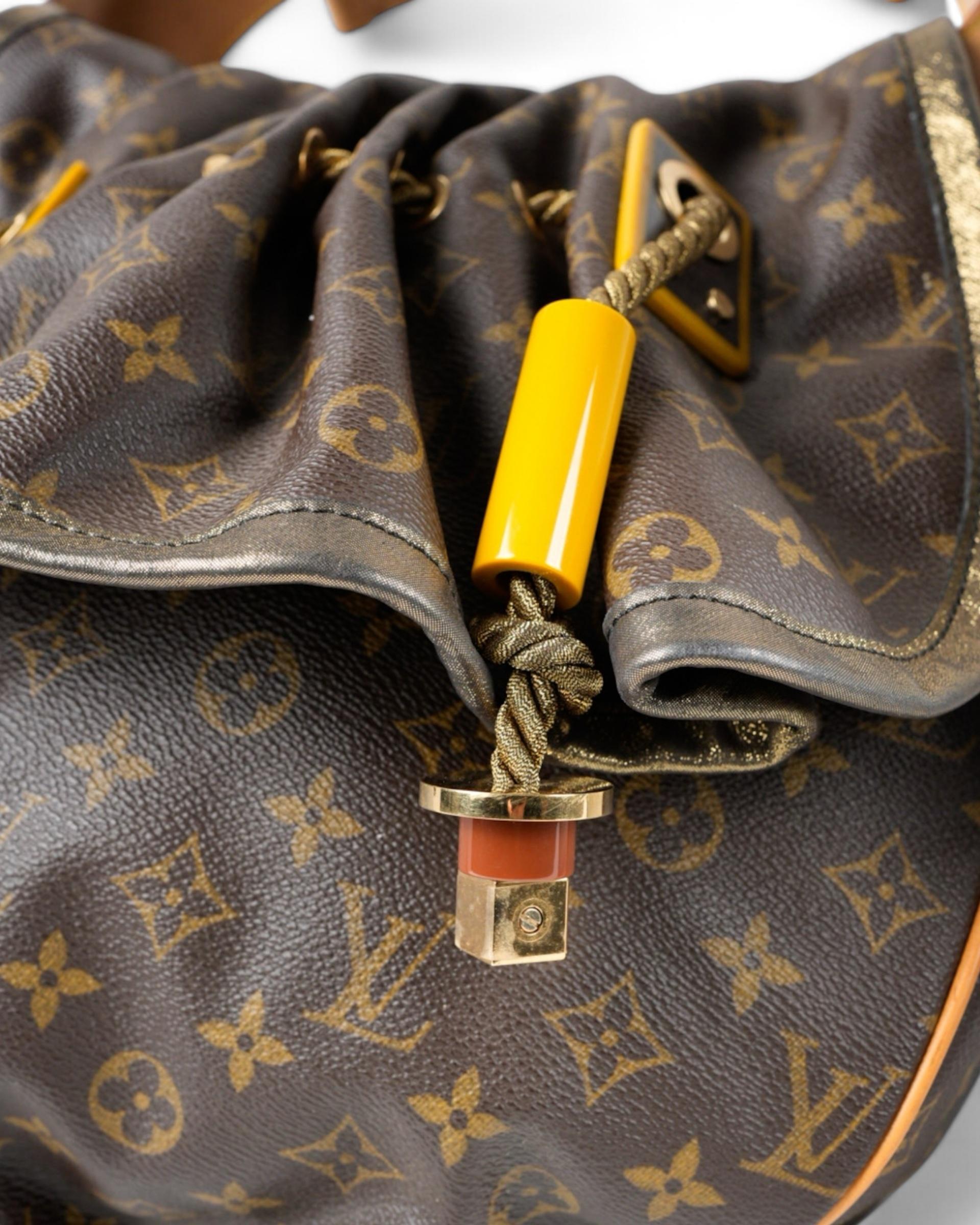 Louis Vuitton signature bag, model Kalahari in size MM, made of brown canvas with elegant cowhide inserts and gold hardware. The bag features a front flap without a closure, giving it a practical and refined design. The interior, lined with soft