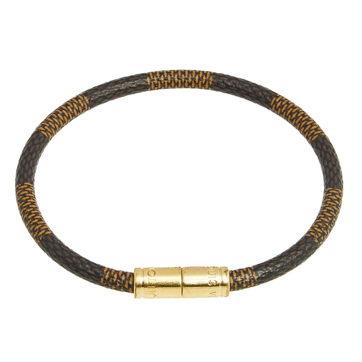 Simple yet elegant, this 'Keep It' bracelet is designed with the label's signature Damier Ebene canvas body and features a gold-tone center. Wear it as a stand-alone piece or stack it with similar bands for a more edgy feel.

