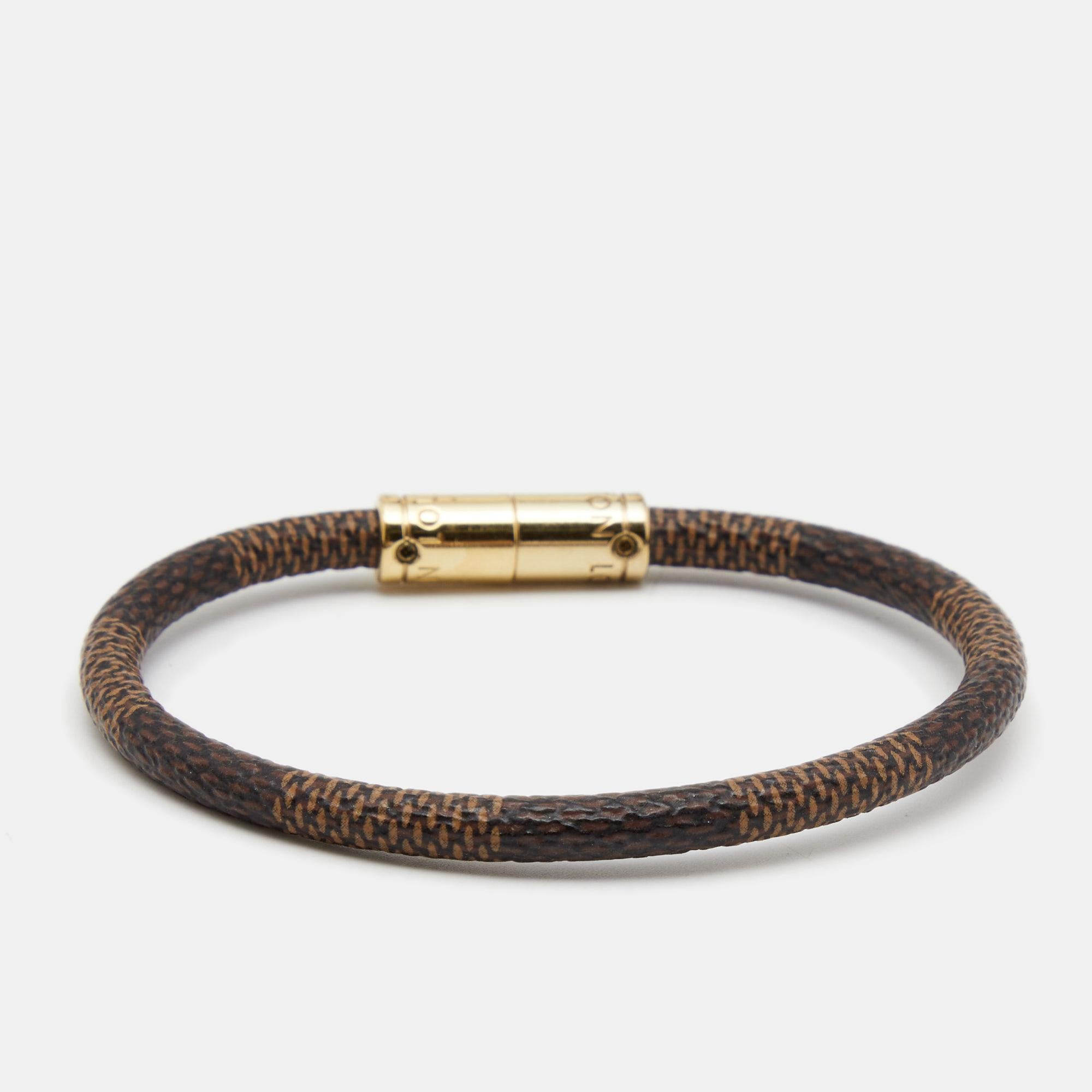 Simple yet elegant, this 'Keep It' bracelet is designed with the label's signature Damier Graphite canvas body and features a gold-tone centre. Wear it as a stand-alone piece or stack it with similar bands for a more edgy feel.

