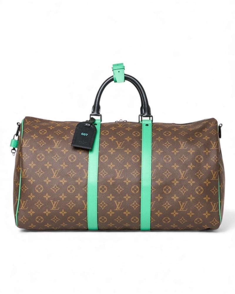 Borsa da viaggio firmata Louis Vuitton, modello Keepall Bandoulière, misura 50, realizzata in tela marrone nella classica fantasia Monogram con inserti in macassar verdi e neri, con minuteria nera. Dotato di una chiusura superiore con zip,