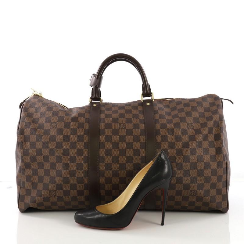 This Louis Vuitton Keepall Bag Damier 50, crafted in damier ebene coated canvas, features dual rolled handles and gold-tone hardware. Its dual-zip closure opens to a brown fabric interior. Authenticity code reads: MB4089. **Note: Shoe photographed