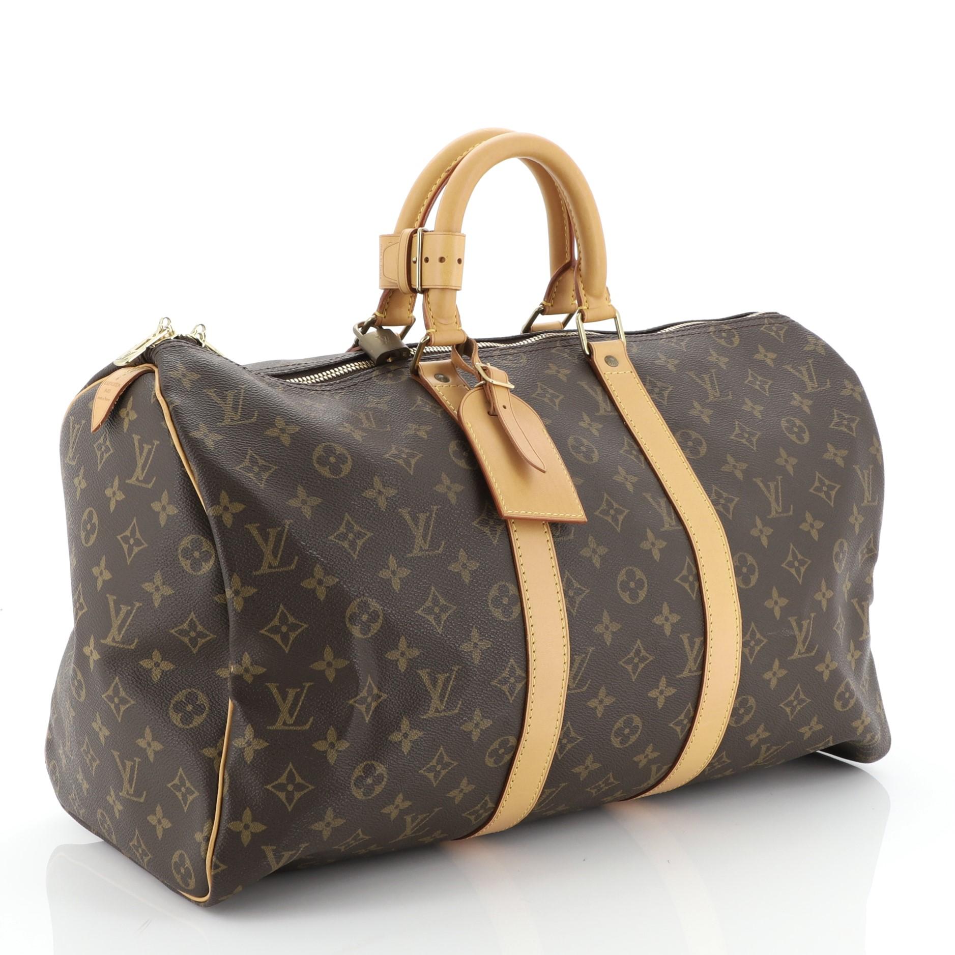 This Louis Vuitton Keepall Bag Monogram Canvas 45, crafted in brown monogram coated canvas, features dual rolled leather handles, vachetta leather trim, and gold-tone hardware. Its two-way zip closure opens to a brown fabric interior. Authenticity