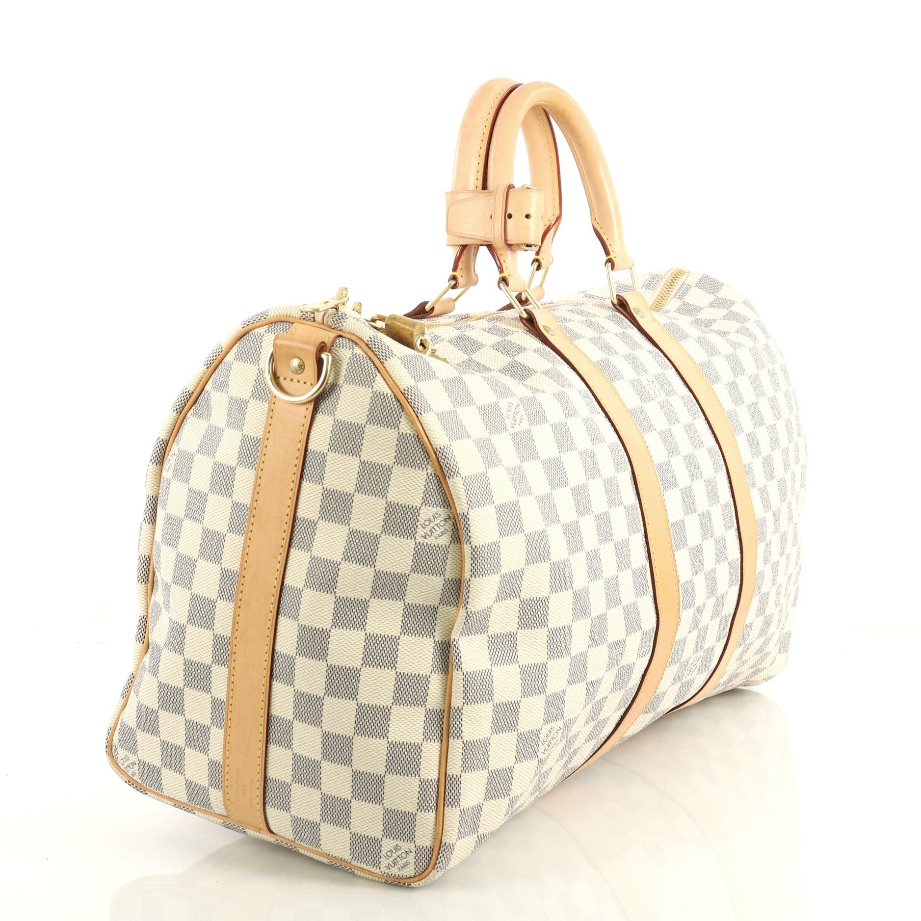 This Louis Vuitton Keepall Bandouliere Bag Damier 45, crafted from damier azur coated canvas, features dual rolled handles, leather trim, and gold-tone hardware. Its two-way top zip closure opens to a neutral fabric interior. Authenticity code