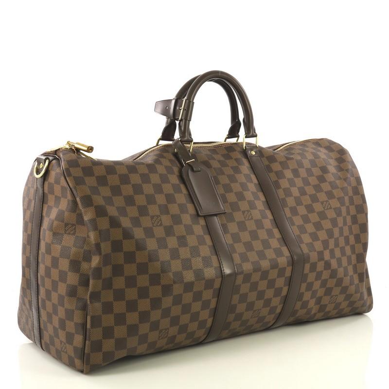 This Louis Vuitton Keepall Bandouliere Bag Damier 55, crafted with damier ebene coated canvas, features dual rolled handles, leather trim, and gold-tone hardware. Its zip closure opens to a brown fabric interior . Authenticity code reads: MB1142.