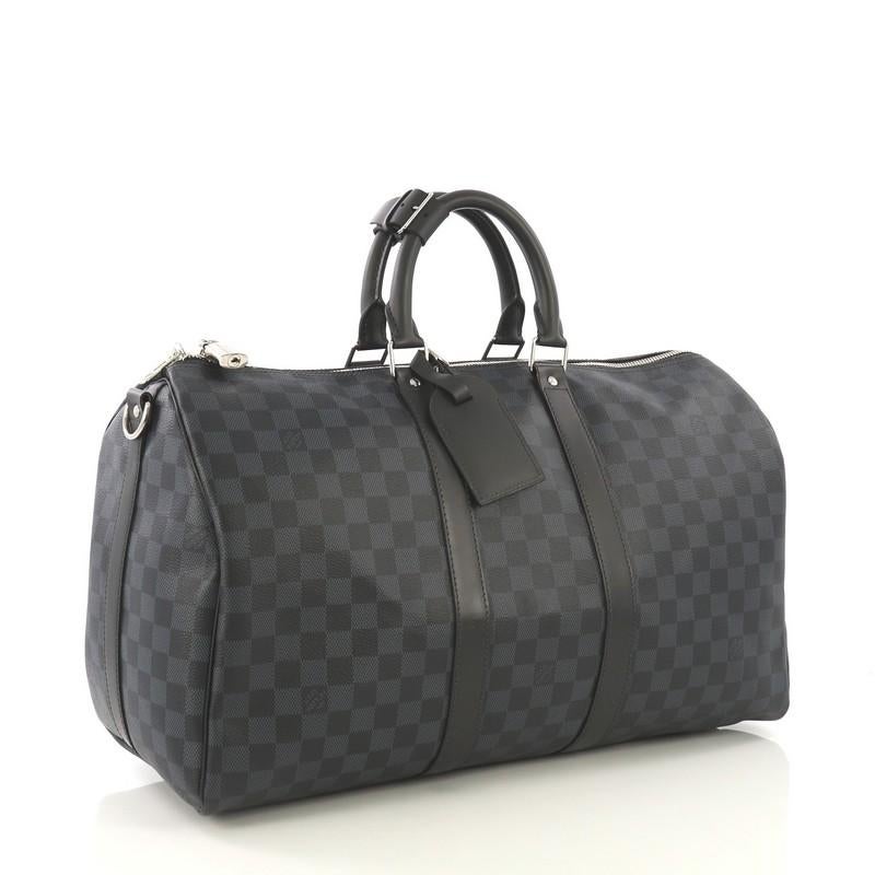 This Louis Vuitton Keepall Bandouliere Bag Damier Cobalt 45, Crafted with damier cobalt coated canvas, features dual rolled handles, leather trim, and silver-tone hardware. Its zip closure opens to a black fabric interior. Authenticity code reads: