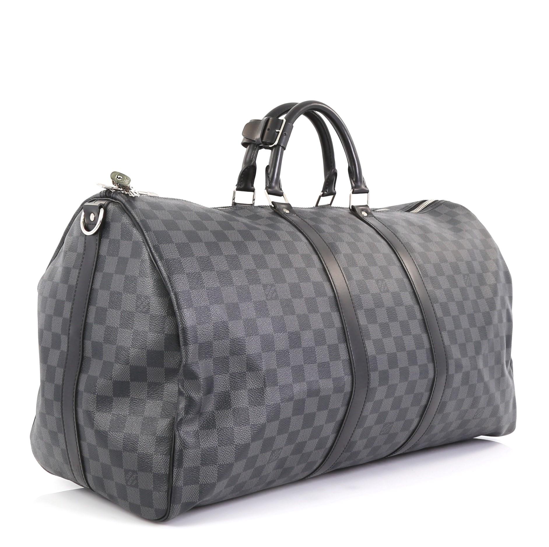 This Louis Vuitton Keepall Bandouliere Bag Damier Graphite 55, crafted with damier graphite coated canvas, features dual rolled handles, leather trim, and silver-tone hardware. Its zip closure opens to a black fabric interior. Authenticity code
