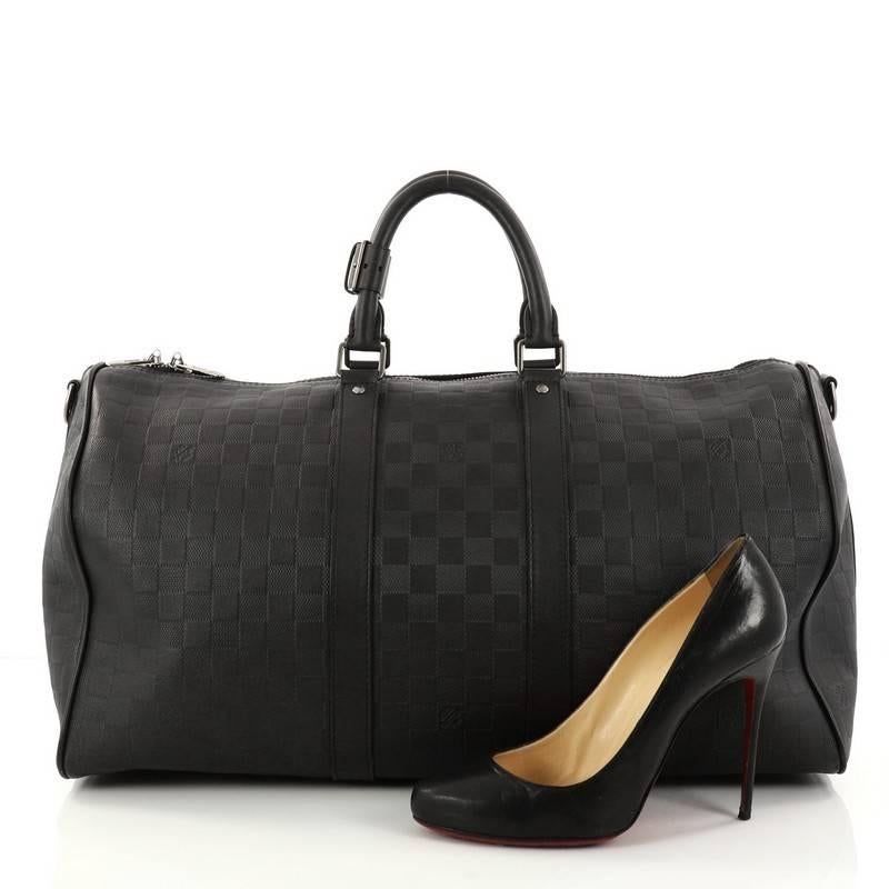 This authentic Louis Vuitton Keepall Bandouliere Bag Damier Infini Leather 45 is the perfect purchase for a weekend trip, and can be effortlessly paired with any outfit from casual to formal. Crafted from Louis Vuitton black damier infini leather,