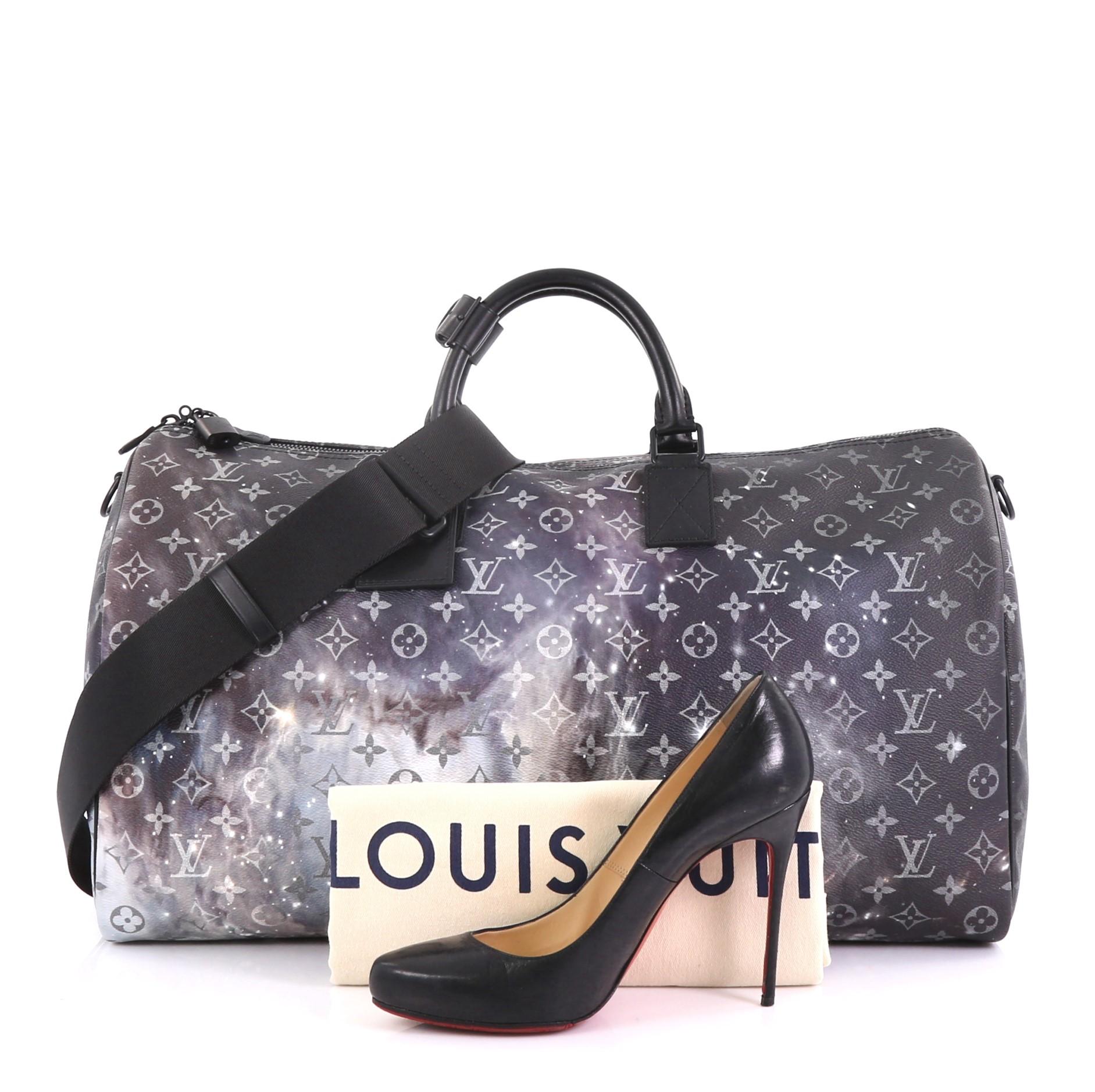 This Louis Vuitton Keepall Bandouliere Bag Limited Edition Monogram Galaxy Canvas 50, crafted in monogram Galaxy coated canvas, features dual rolled leather handles, leather trim, and matte black-tone hardware. Its zip closure opens to a black