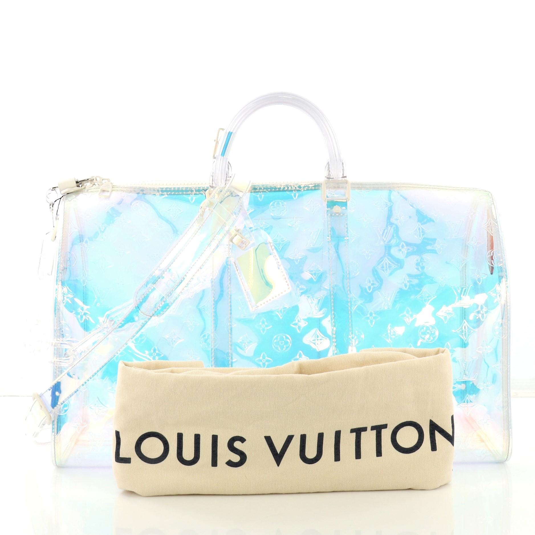 This Louis Vuitton Keepall Bandouliere Bag Limited Edition Monogram Prism PVC 50, crafted in multicolor iridescent monogram prism PVC, features dual rolled handles, resin chain, and silver-tone hardware. Its zip closure opens to a multicolor