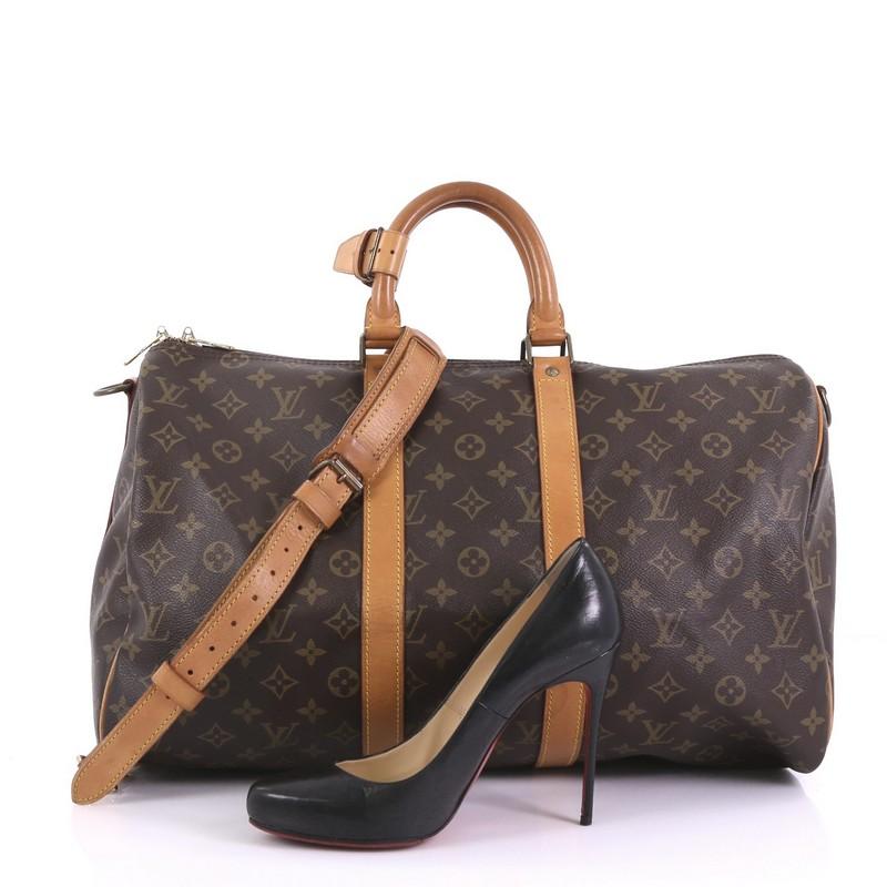 This Louis Vuitton Keepall Bandouliere Bag Monogram Canvas 45, crafted from brown monogram coated canvas, features dual rolled handles, natural cowhide leather trim, and gold-tone hardware. Its zip closure opens to a brown fabric interior.