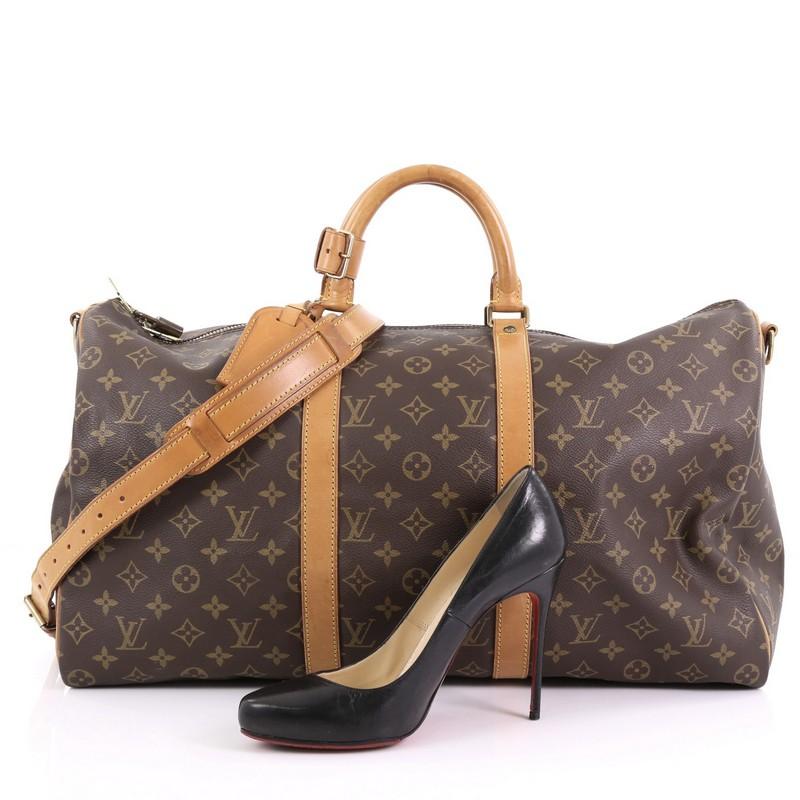 This Louis Vuitton Keepall Bandouliere Bag Monogram Canvas 50, crafted from brown monogram coated canvas, features dual rolled handles, natural cowhide leather trims, and gold-tone hardware. Its zip closure opens to a brown fabric interior.