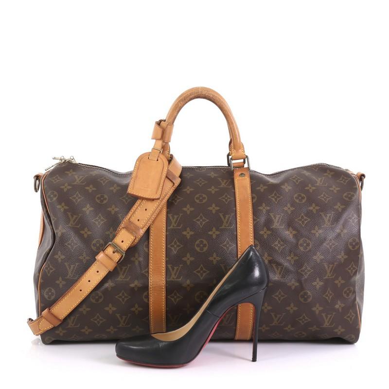 This Louis Vuitton Keepall Bandouliere Bag Monogram Canvas 50, crafted from brown monogram coated canvas, features dual rolled handles, natural cowhide leather trim, and gold-tone hardware. Its zip closure opens to a brown fabric interior.