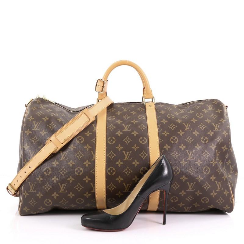 This Louis Vuitton Keepall Bandouliere Bag Monogram Canvas 55, crafted from brown monogram coated canvas, features dual rolled handles, natural cowhide leather trims, and gold-tone hardware. Its zip closure opens to a brown fabric interior.