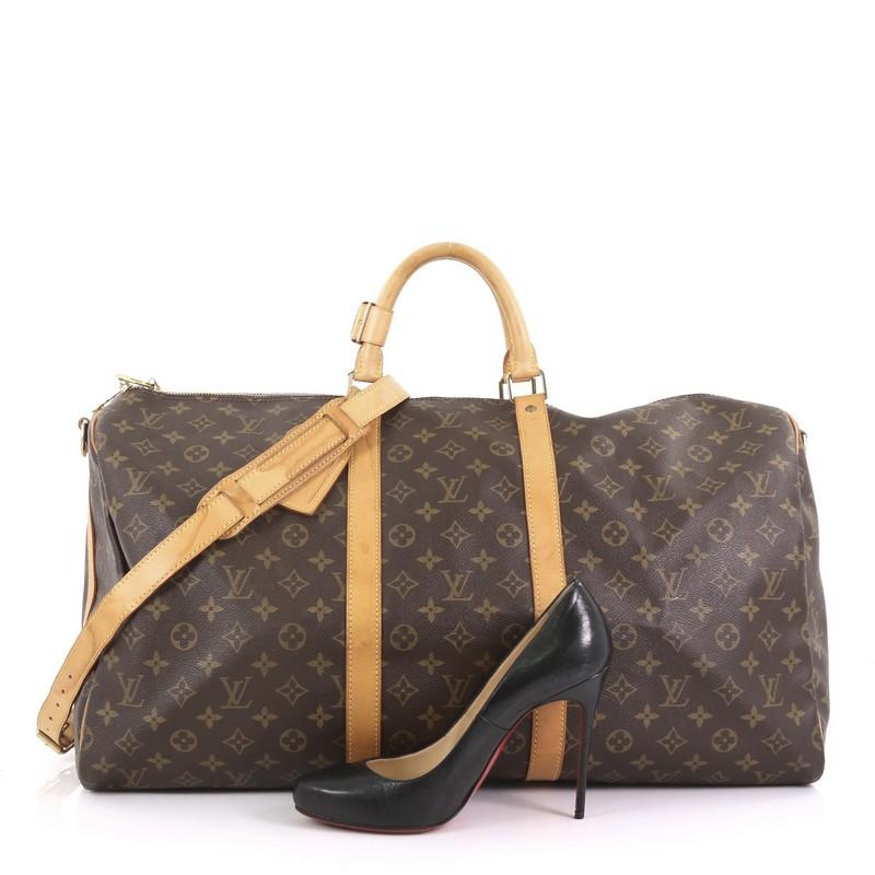 This Louis Vuitton Keepall Bandouliere Bag Monogram Canvas 55, crafted from brown monogram coated canvas, features dual rolled handles, natural cowhide leather trim, and gold-tone hardware. Its zip closure opens to a brown fabric interior.