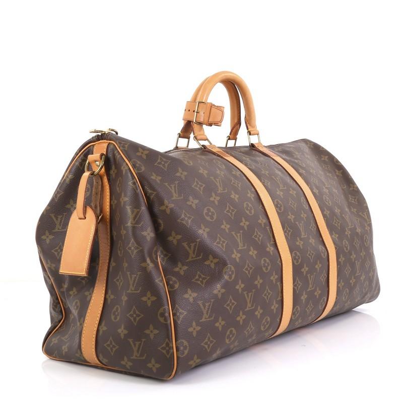 This Louis Vuitton Keepall Bandouliere Bag Monogram Canvas 55, crafted from brown monogram coated canvas, features dual rolled handles, natural cowhide leather trim, and gold-tone hardware. Its zip closure opens to a brown fabric interior.