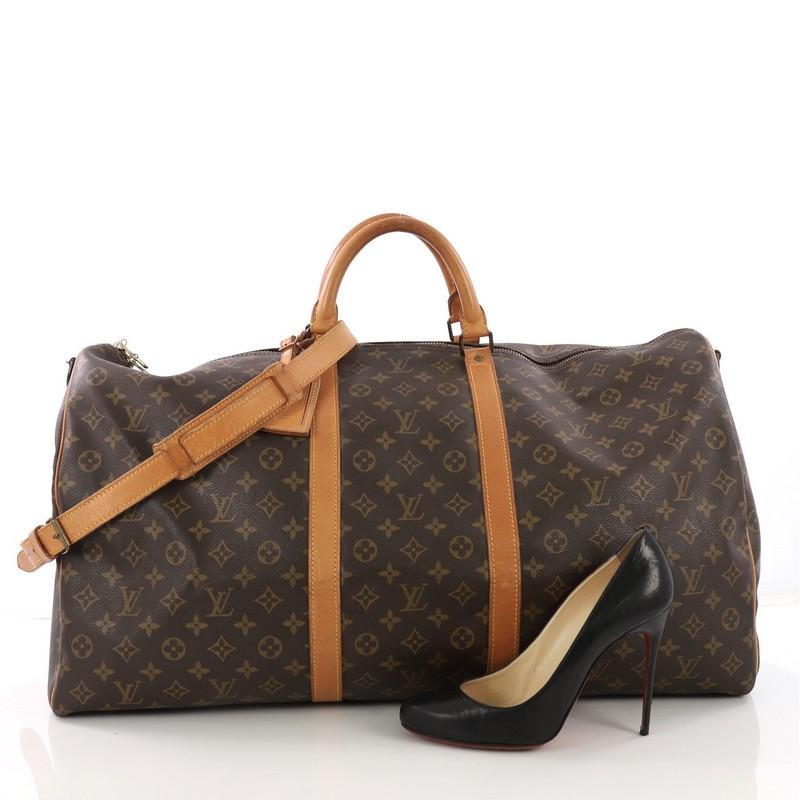 This Louis Vuitton Keepall Bandouliere Bag Monogram Canvas 60, crafted from brown monogram coated canvas, features dual rolled handles, natural cowhide leather trims, and gold-tone hardware. Its zip closure opens to a brown fabric interior.
