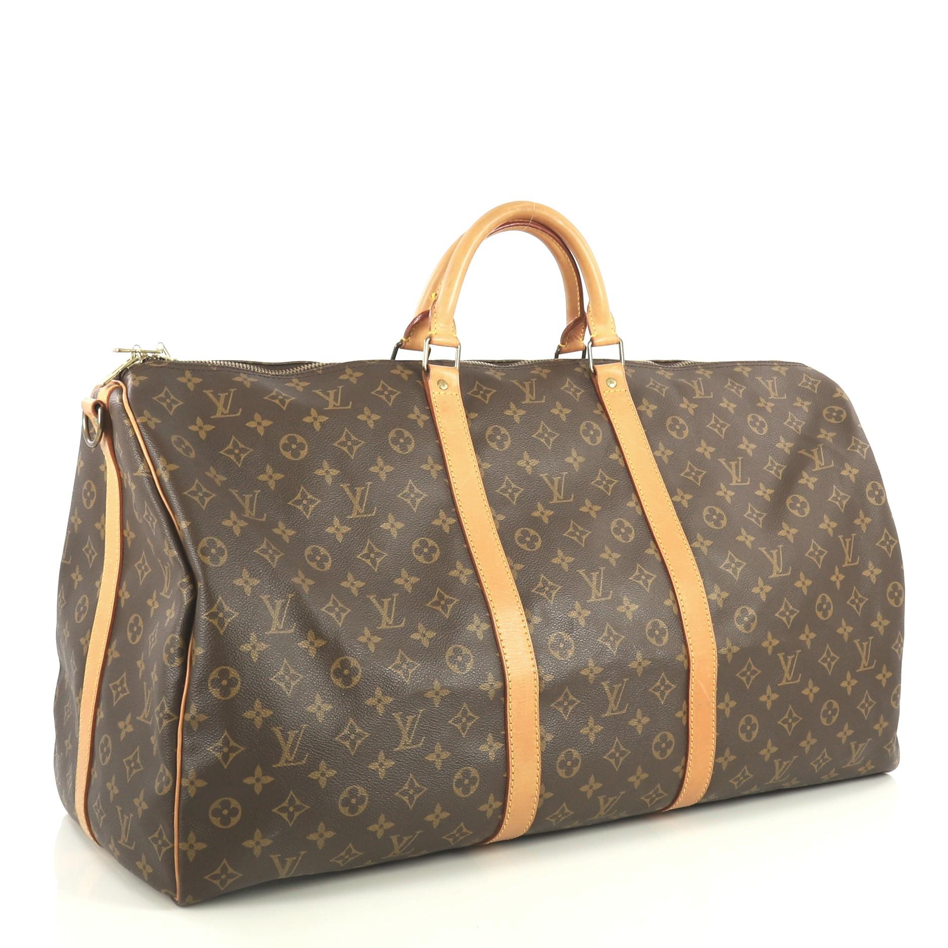 This Louis Vuitton Keepall Bandouliere Bag Monogram Canvas 60, crafted from brown monogram coated canvas, features dual rolled handles, cowhide leather trim, and gold-tone hardware. Its zip closure opens to a brown fabric interior. Authenticity code