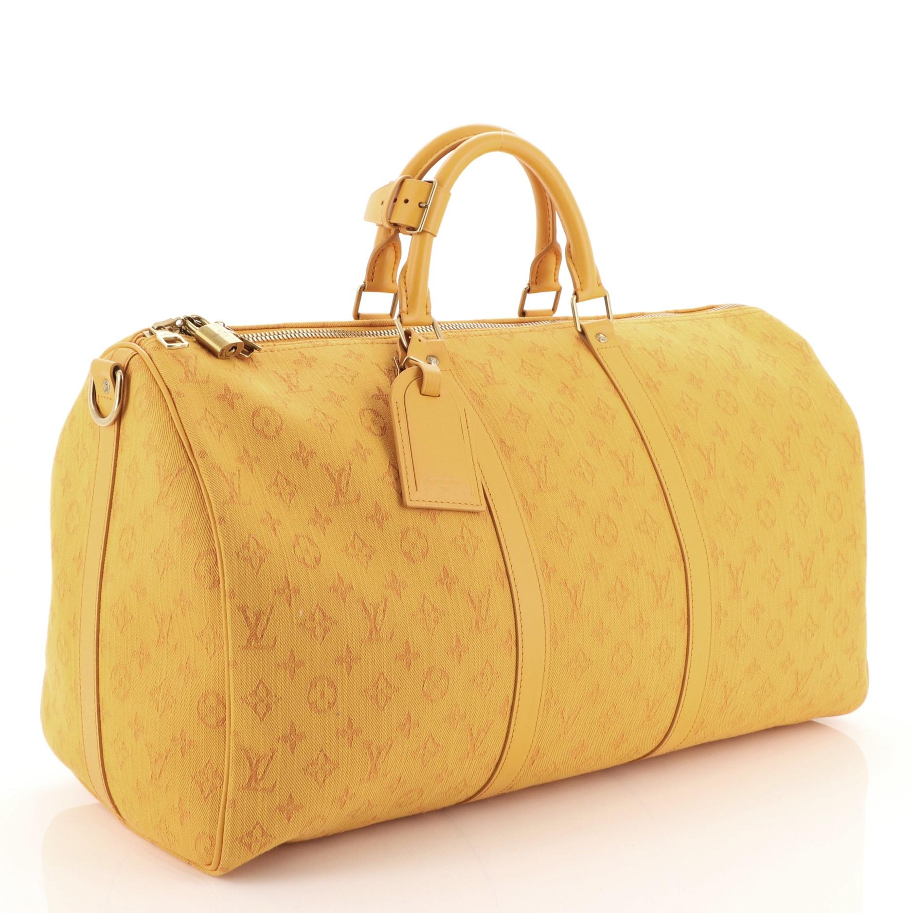This Louis Vuitton Keepall Bandouliere Bag Monogram Denim 50, crafted from yellow denim, features dual rolled handles, natural leather trim, and gold-tone hardware. Its zip closure opens to a yellow fabric interior with zip pocket. Authenticity code