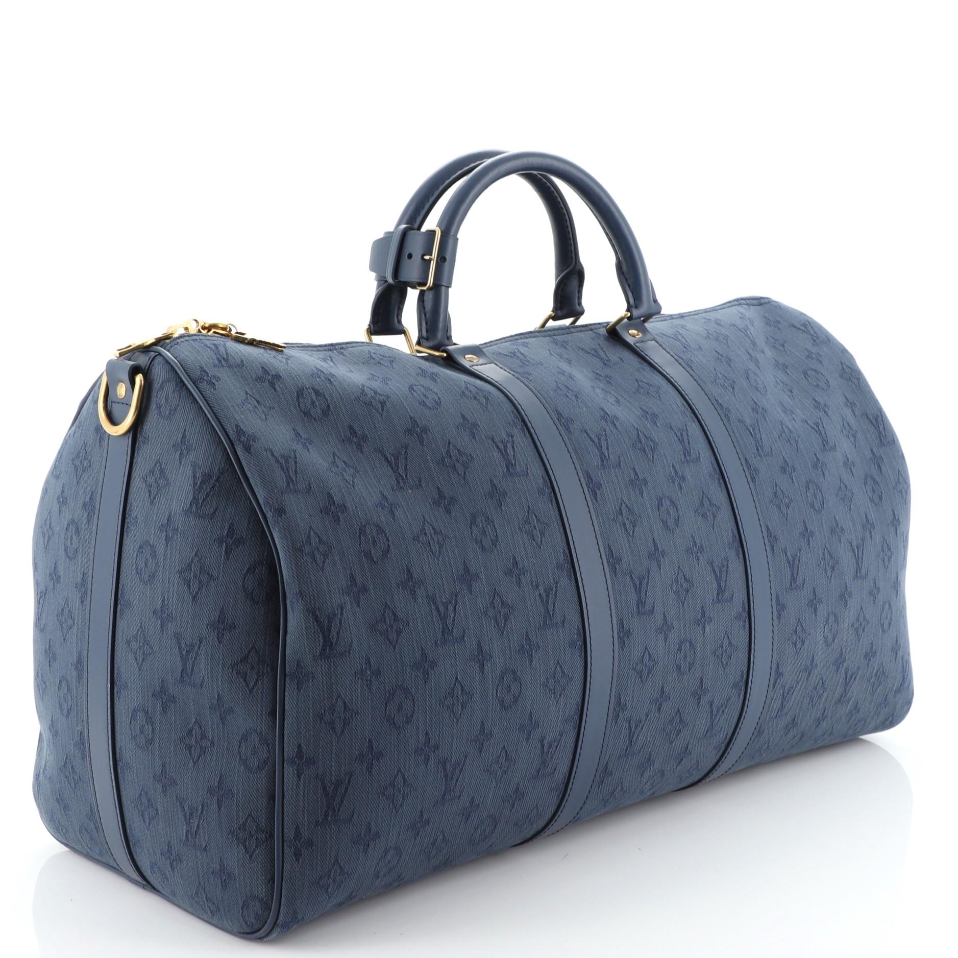 This Louis Vuitton Keepall Bandouliere Bag Monogram Denim 50, crafted from blue monogram denim, features dual rolled handles, leather trim, and gold-tone hardware. Its zip closure opens to a blue fabric interior with zip pocket. Authenticity code