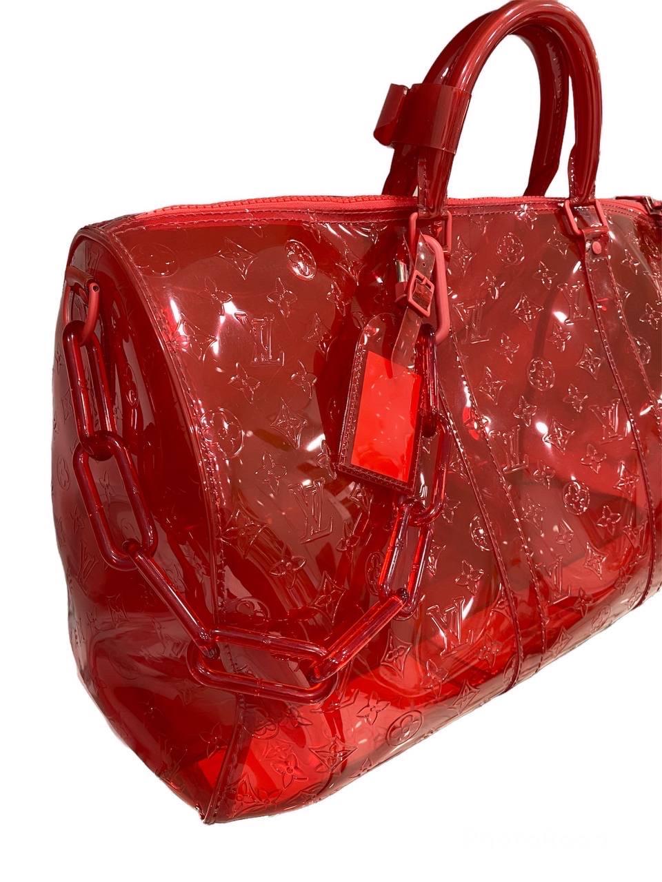 Louis Vuitton x Virgil Abloh Keepall Bandouliere 50 Limited Edition SS19 iconic bag in embossed transparent red PVC Monogram with silver hardware.

It has a central opening with a zip closure equipped with a special padlock with keys. Very large