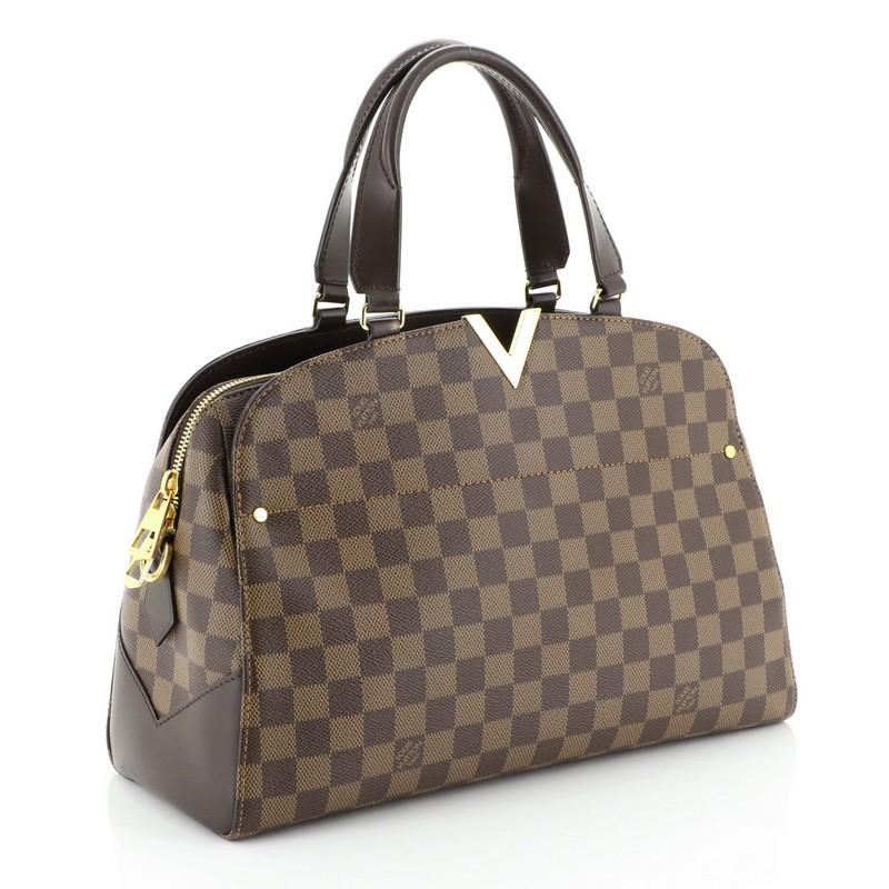 This Louis Vuitton Kensington Bowling Bag Damier, crafted from damier ebene coated canvas, features dual leather handles, leather trim, cut out V hardware on its top center, and gold-tone hardware. Its zip closure opens to a neutral microfiber