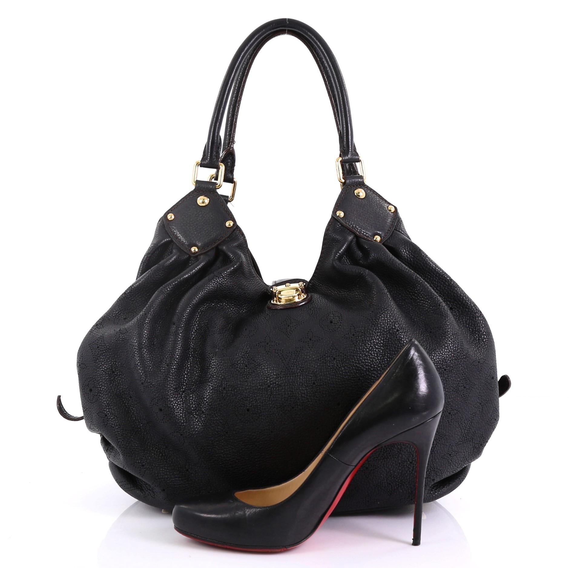 This Louis Vuitton L Hobo Mahina Leather, crafted from black monogram mahina leather, features dual rolled handles, buckle and stud details, and gold-tone hardware. Its engraved top flap push-lock closure opens to a brown microfiber interior with