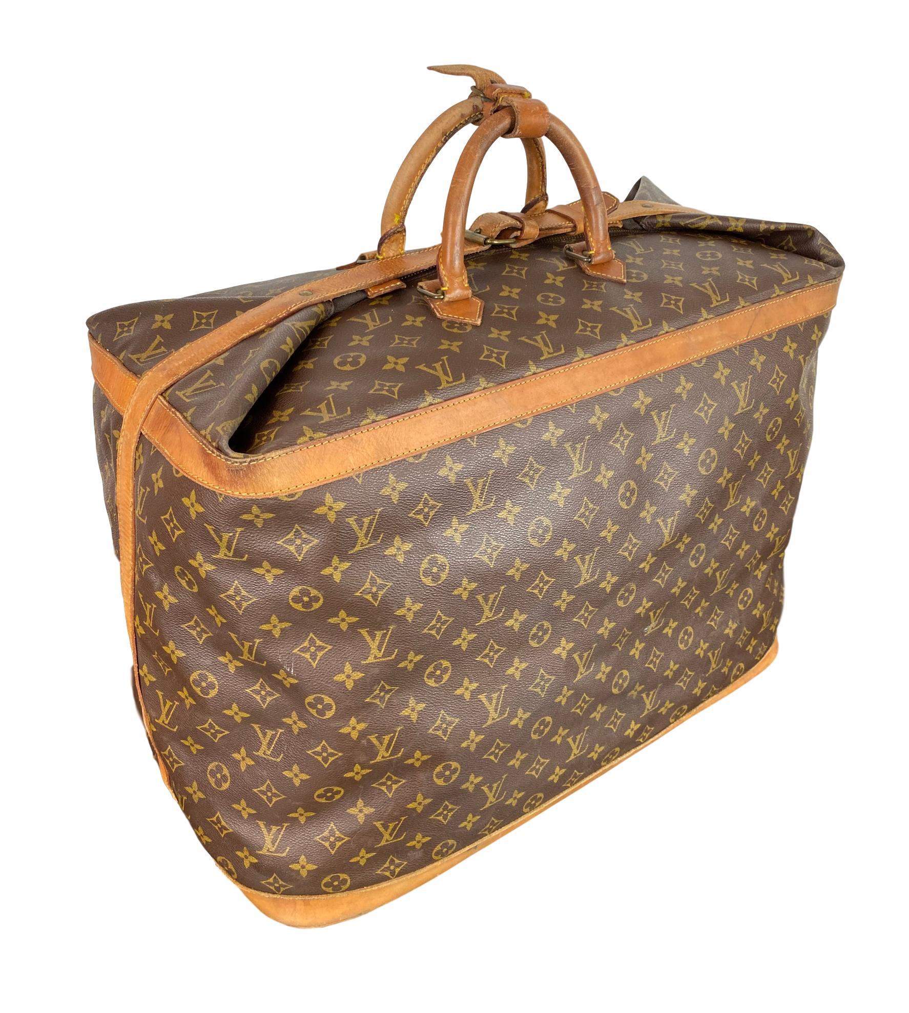 Vintage Louis Vuitton Large 55 Cruiser Travel Bag, France September 1990. This vintage bag comes in the classic Louis Vuitton Monogram canvas with rolled top vachetta handles with a strap closure as well as folded flap that buckles the entirety of