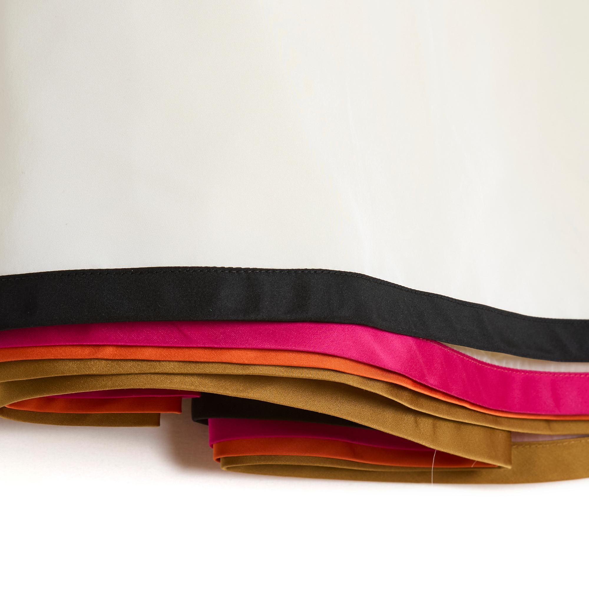 Jupe Louis Vuitton (par Marc Jacobs) coupe droite, légèrement évasée sur le devant et larges plis au dos, composée de plusieurs couches ou volants, le bas 3 en crêpe polyamide écru clair ourlé de rubans marron, orange et rose, le haut jupe en