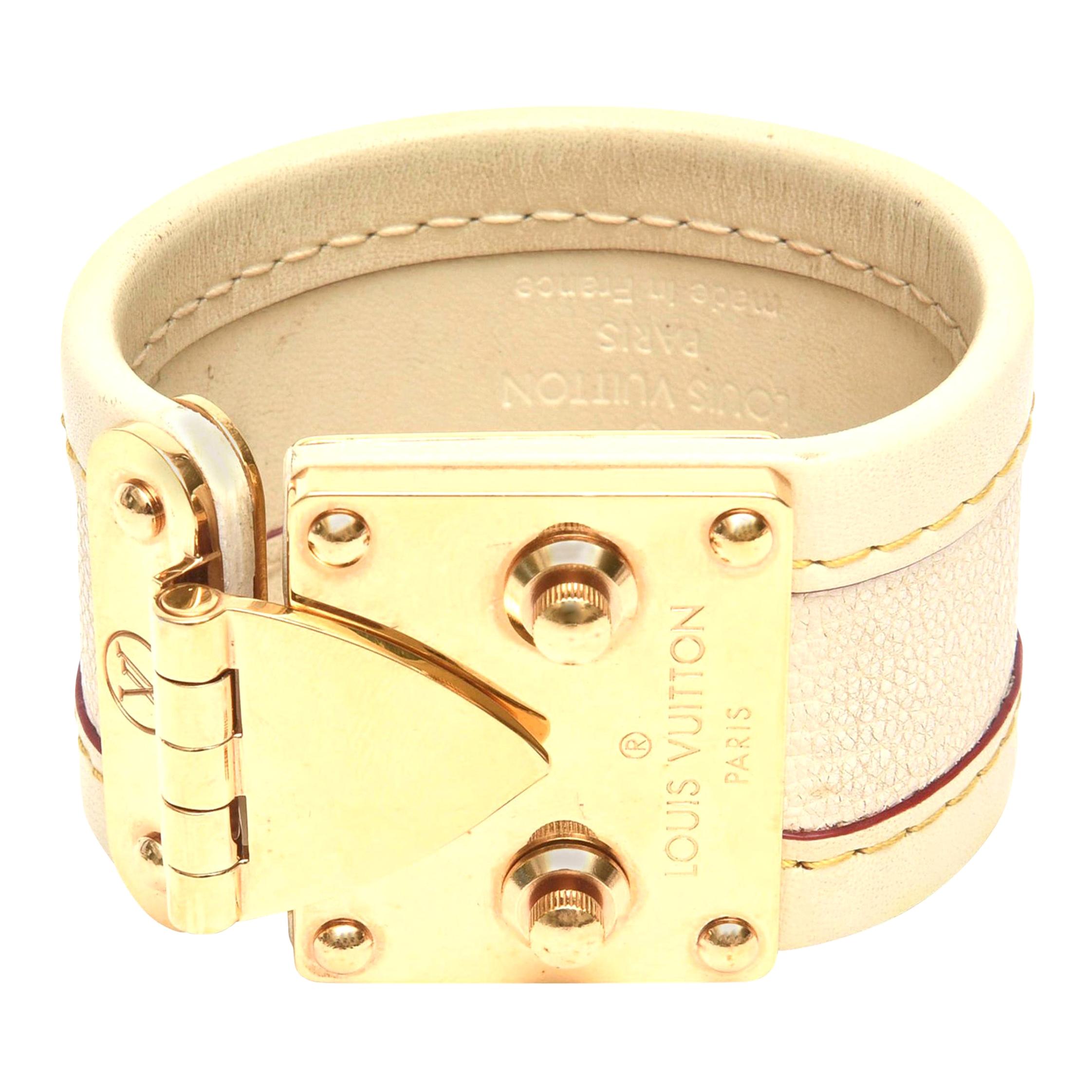 This iconic cuff bracelet by Louis Vuitton is beige stitched leather with beautiful  gold plated brass hardware class and closures. Signed Louis Vuitton Paris on the brass hardware closure. Fits snug to the wrist of one that is of small wrist like a
