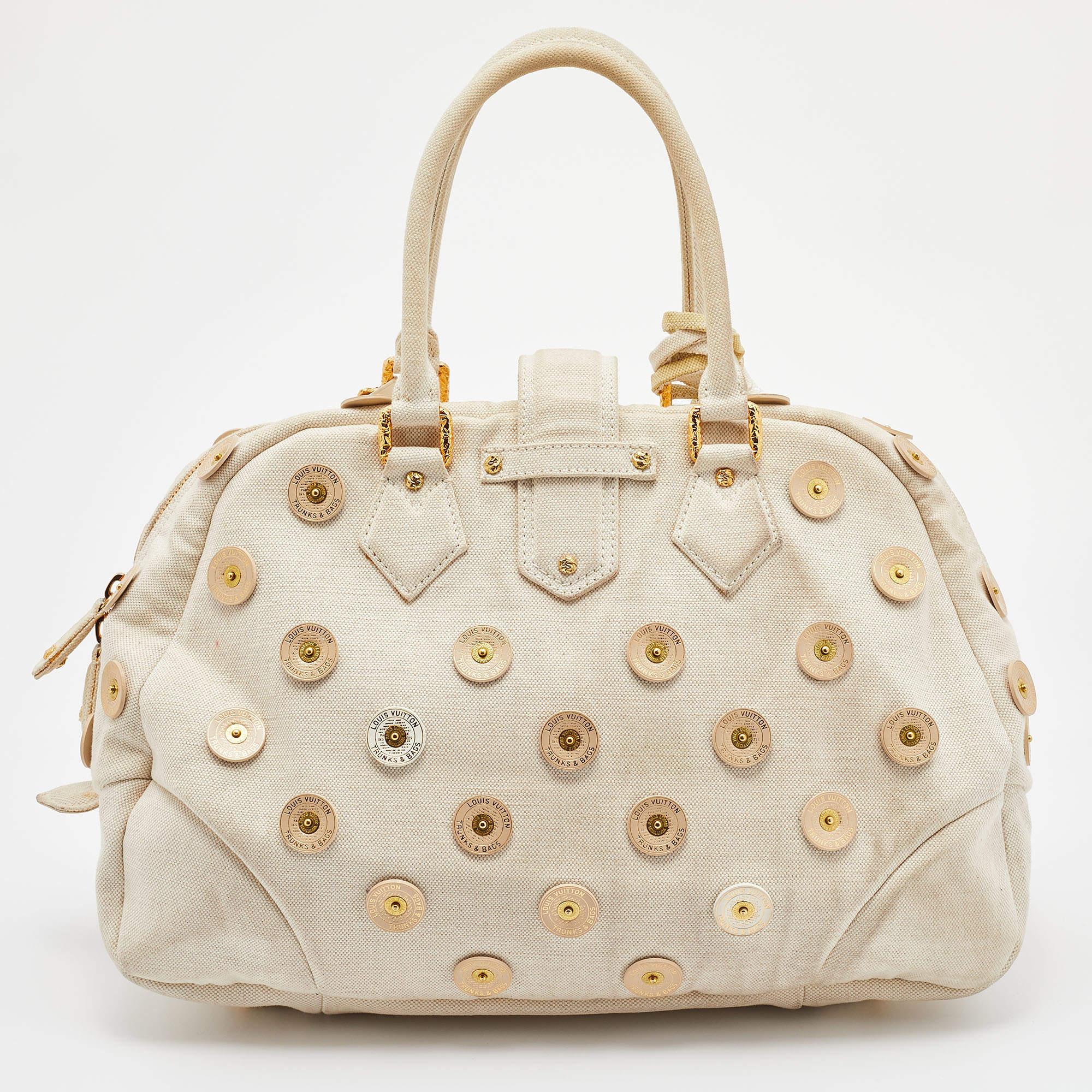 Louis Vuitton's handbags are popular owing to their high style and functionality. Crafted from canvas, this Bowly Panama bag has a beautiful polka dot design all over. The pretty bag features dual top handles, a tag, a textured lock on the front,