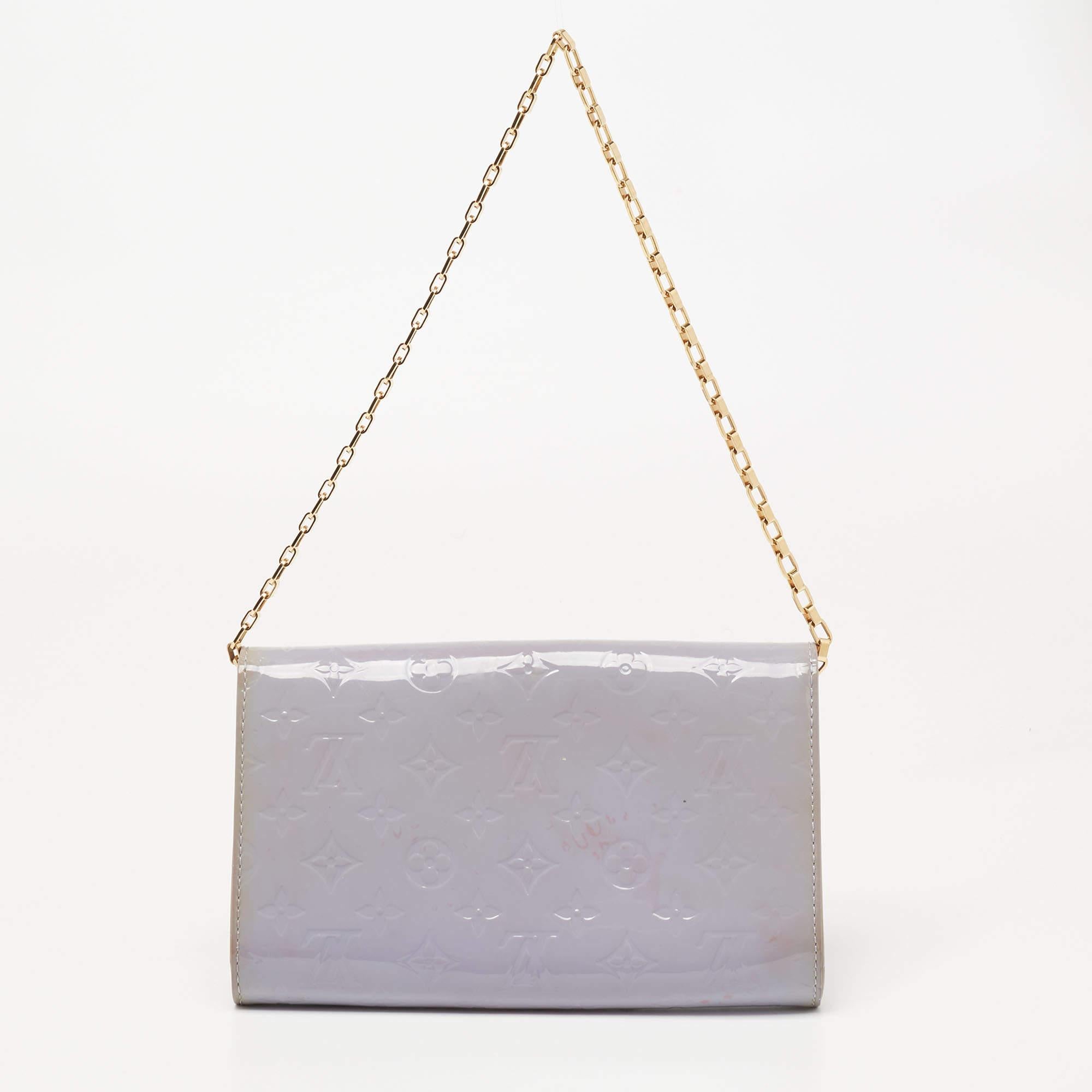 Coming from the House of Louis Vuitton, this Ana clutch bag is all about flaunting luxury and perfection! It is crafted using Lilac Monogram Vernis leather on the exterior and exhibits a leather-fabric interior, gold-tone hardware, and a chain