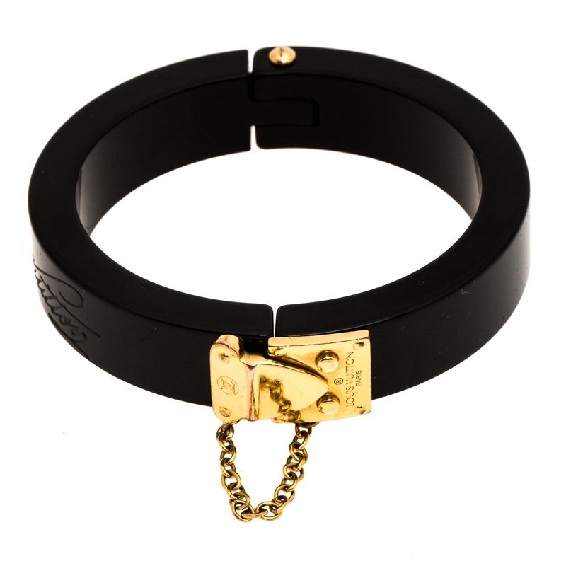 This Lock Me bracelet from Louis Vuitton, exuding a bold finish, will be your new favourite statement accessory. Constructed with resin and gold-tone metal, it features a thick chain accent to the side and a slide lock clasp. It has a sturdy built