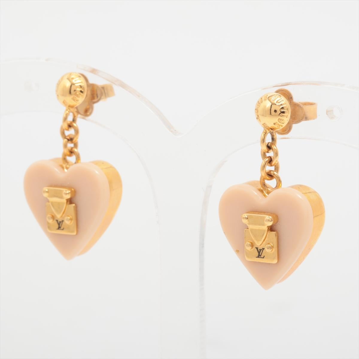 The Louis Vuitton Lock Me Heart Earrings in Pink is a charming and elegant accessory that adds a touch of romance to any ensemble. Crafted from gleaming gold-tone metal, the earring features a delicate heart-shaped motif adorned with the iconic LV