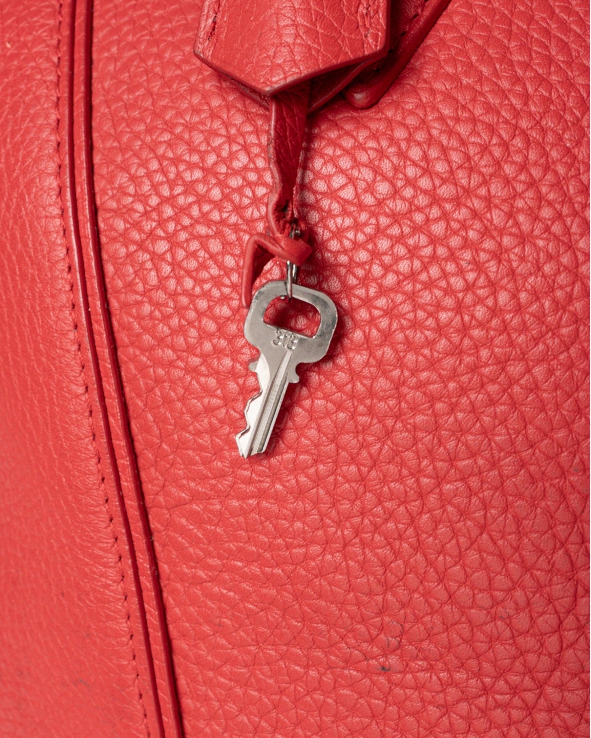 Borsa firmata Louis Vuitton, modello Lockit, misura GM, realizzata in pelle granulata rossa con hardware argentati. Dotata di una chiusura superiore a zip, internamente rivestita in canvas beige con diverse tasche, abbastanza capiente. Munita di