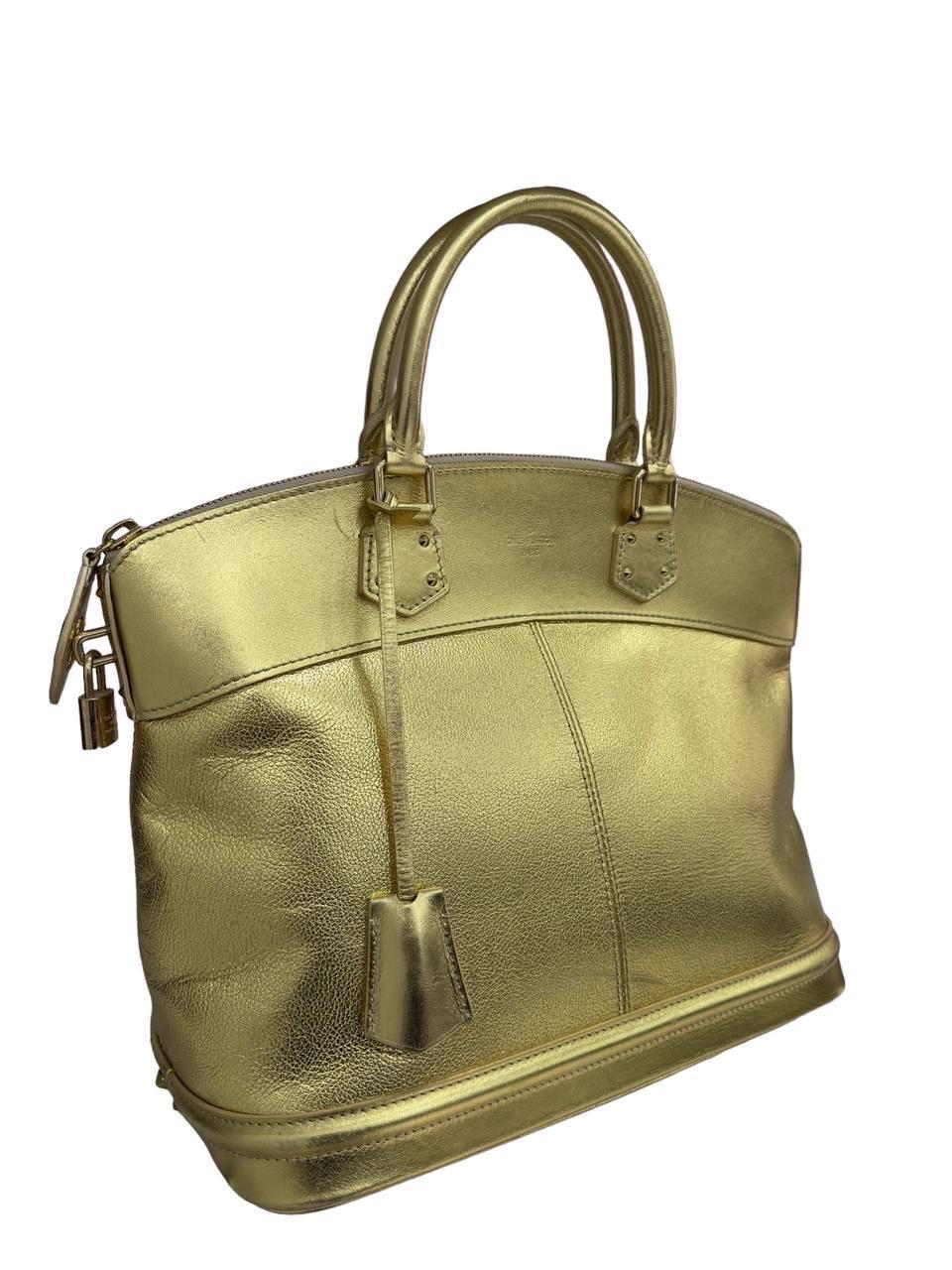 Borsa firmata Louis Vuitton, modello Lockit misura GM, realizzata in pelle oro con hardware oro. Munita di doppio manico rigido per un agevole portata a mano. Dotata di chiusura con zip, con lucchetto e chiavi. Internamente rivestita in tessuto