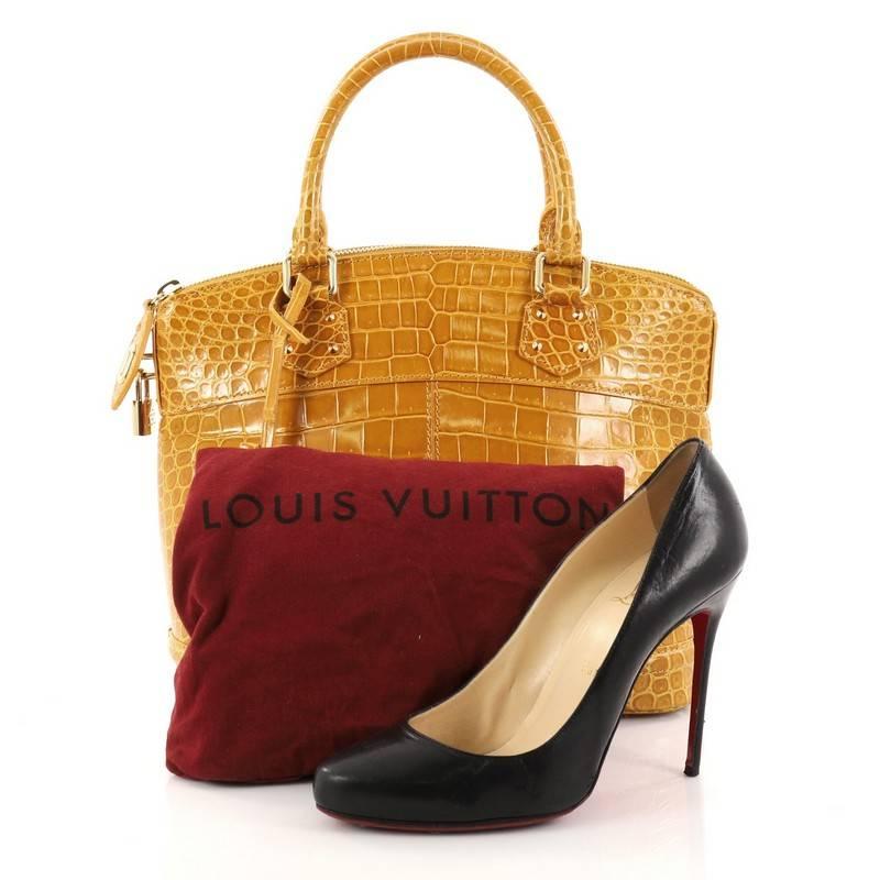 This authentic Louis Vuitton Lockit Handbag Crocodile PM mixes the brand's penchant for timeless designs with modern flair. Crafted from genuine yellow crocodile skin, this chic bag features dual-rolled top handles, protective base studs and